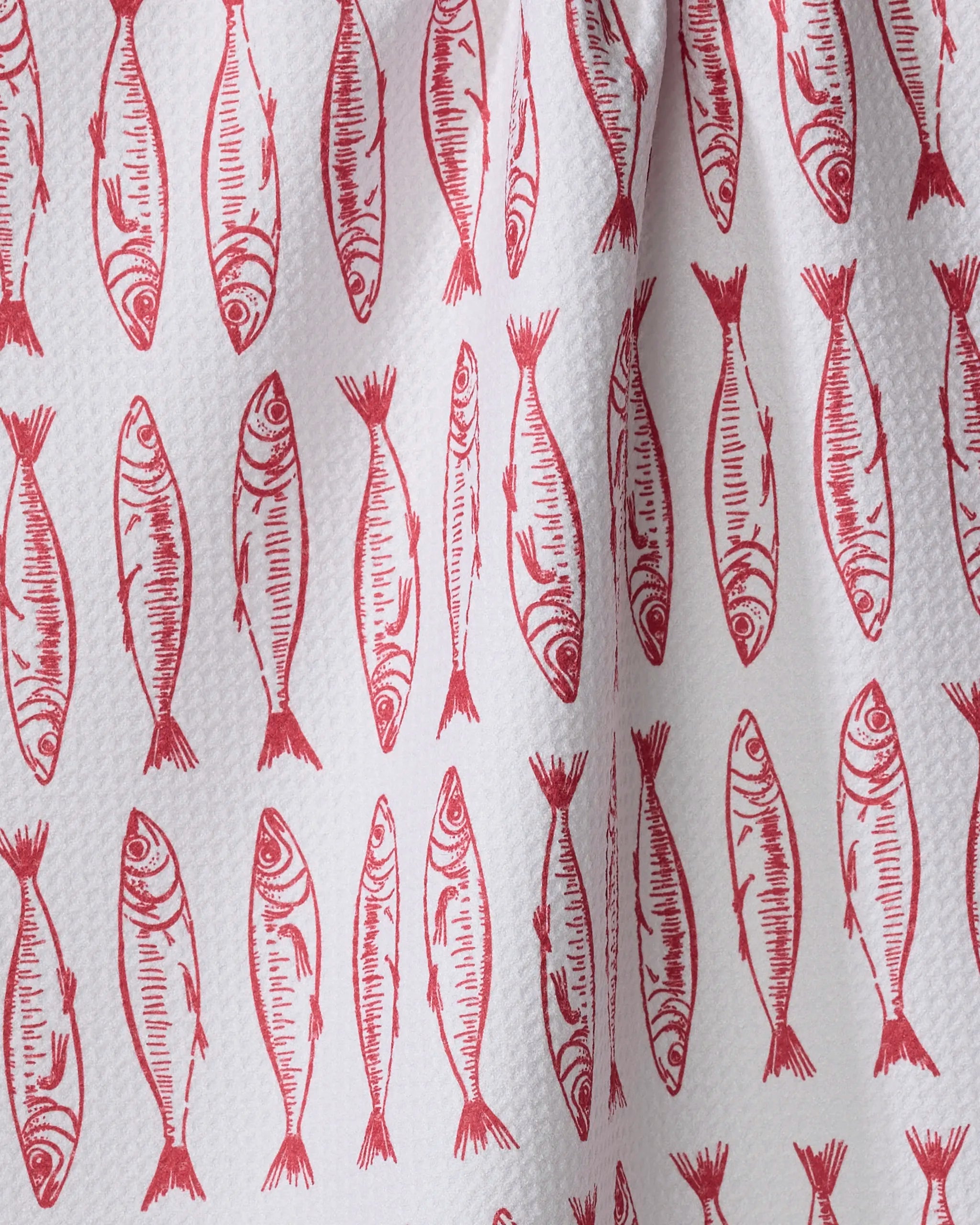 A close-up of Hufton Studio's "Sardine Stripes" tea towel—an eco-friendly white towel with red, hand-drawn sardine illustrations in vertical rows.