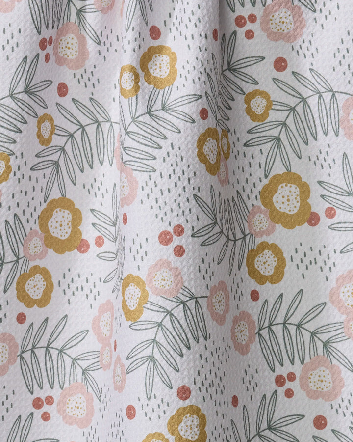 The Savannah Multi kitchen tea towel by Charlie Rowan Designs features yellow and pink flowers, green leaves, and dotted accents on a white textured background. Made from recycled materials, it brings delicate, nature-inspired charm to your space.
