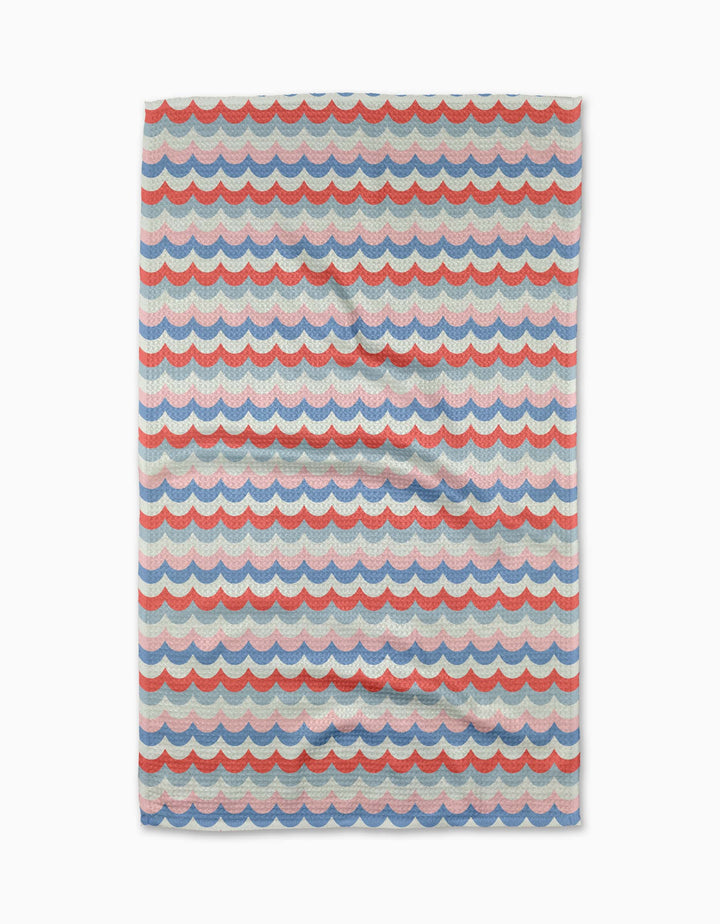 The Geometry Scallop Stripes tea towel is made with Geoweave fabric and features a white background with repeating red, blue, and purple scalloped wave stripes.
