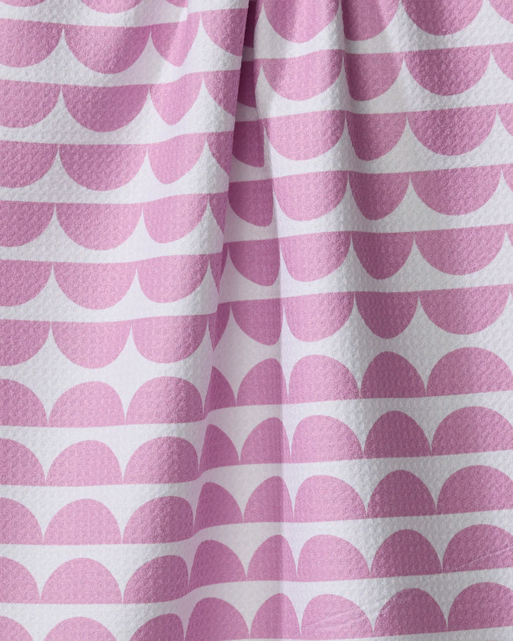Close-up of The Buy Guide’s Scallops - Pink eco-friendly dish towel, featuring a reusable design with soft folds and a repeating pattern of pink semi-circles in horizontal rows on white.