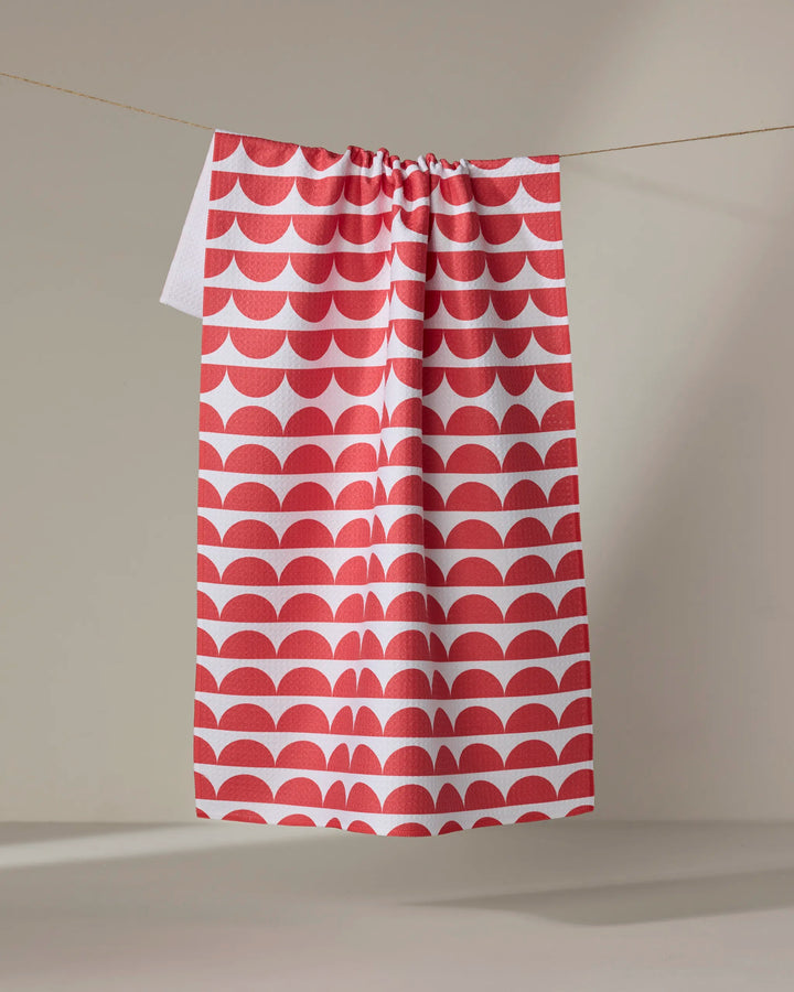 The Buy Guide’s Scallops - Red tea towel, ultra-absorbent and featuring a red and white scallop pattern, hangs from a clothesline against a neutral background.