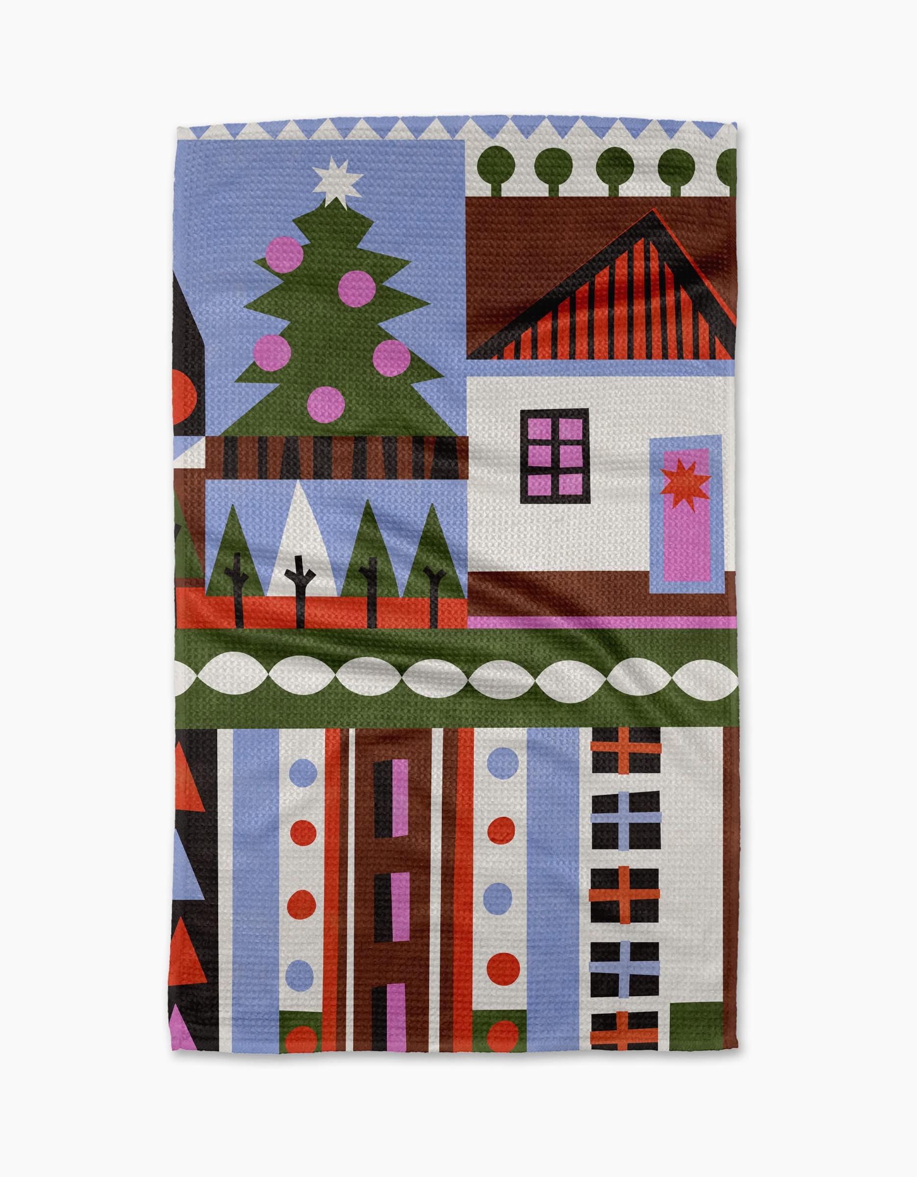 The Scandi Cottage kitchen towel by Claire Iglesias features a festive geometric house with a decorated Christmas tree, vibrant patterns, and shapes in red, green, brown, purple, and white.