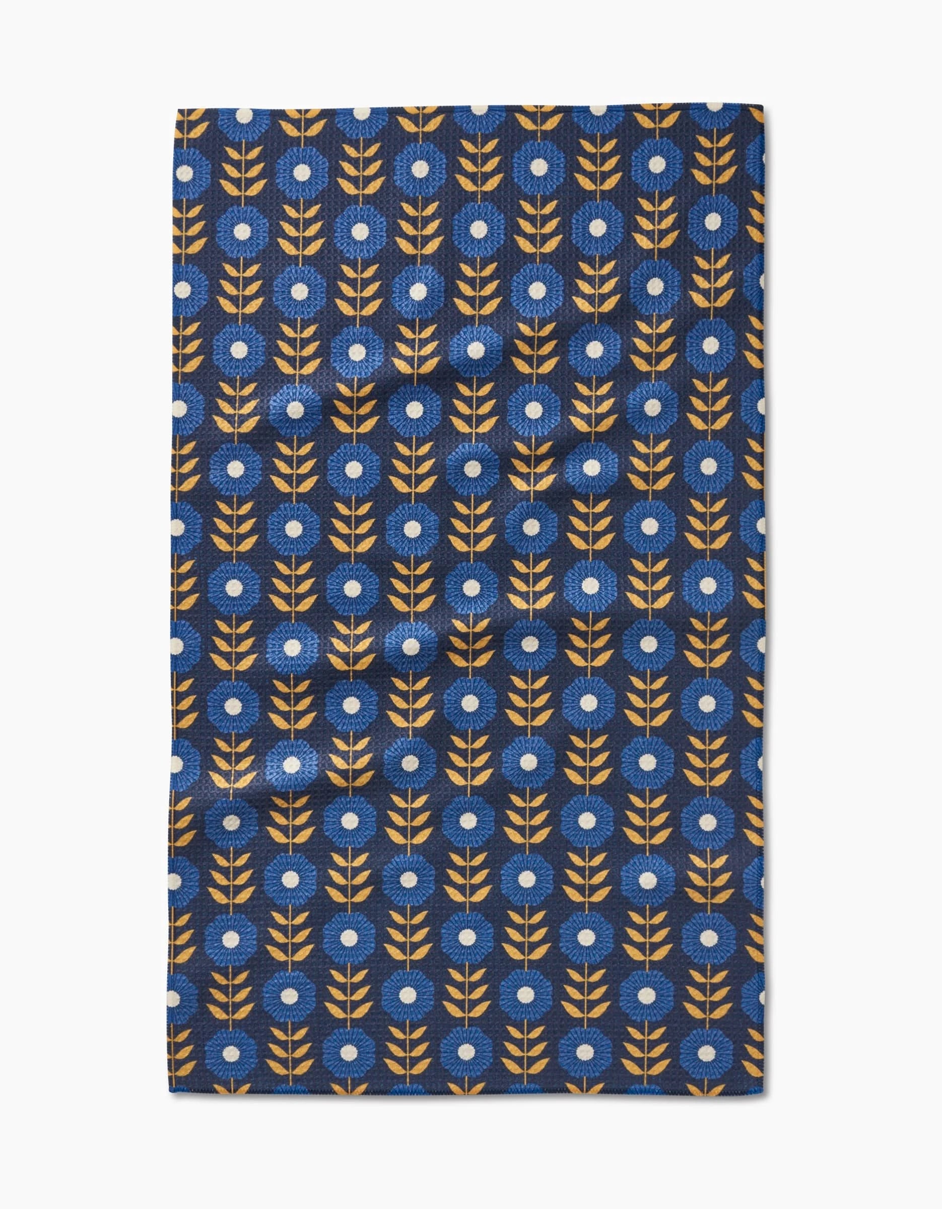The Scandi Floral tea towel by Megan Kampa features stylized orange branches and white-centered blue flowers on dark blue Geoweave fabric, blending geometric beauty with practical function.