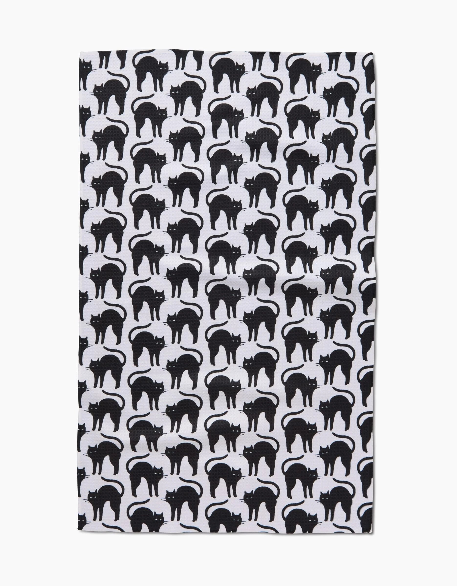 The Scaredy Cat Black tea towel by Hufton Studio is ultra-absorbent, made from recycled materials, and features a repeating pattern of black cats standing leftward on a crisp white background.
