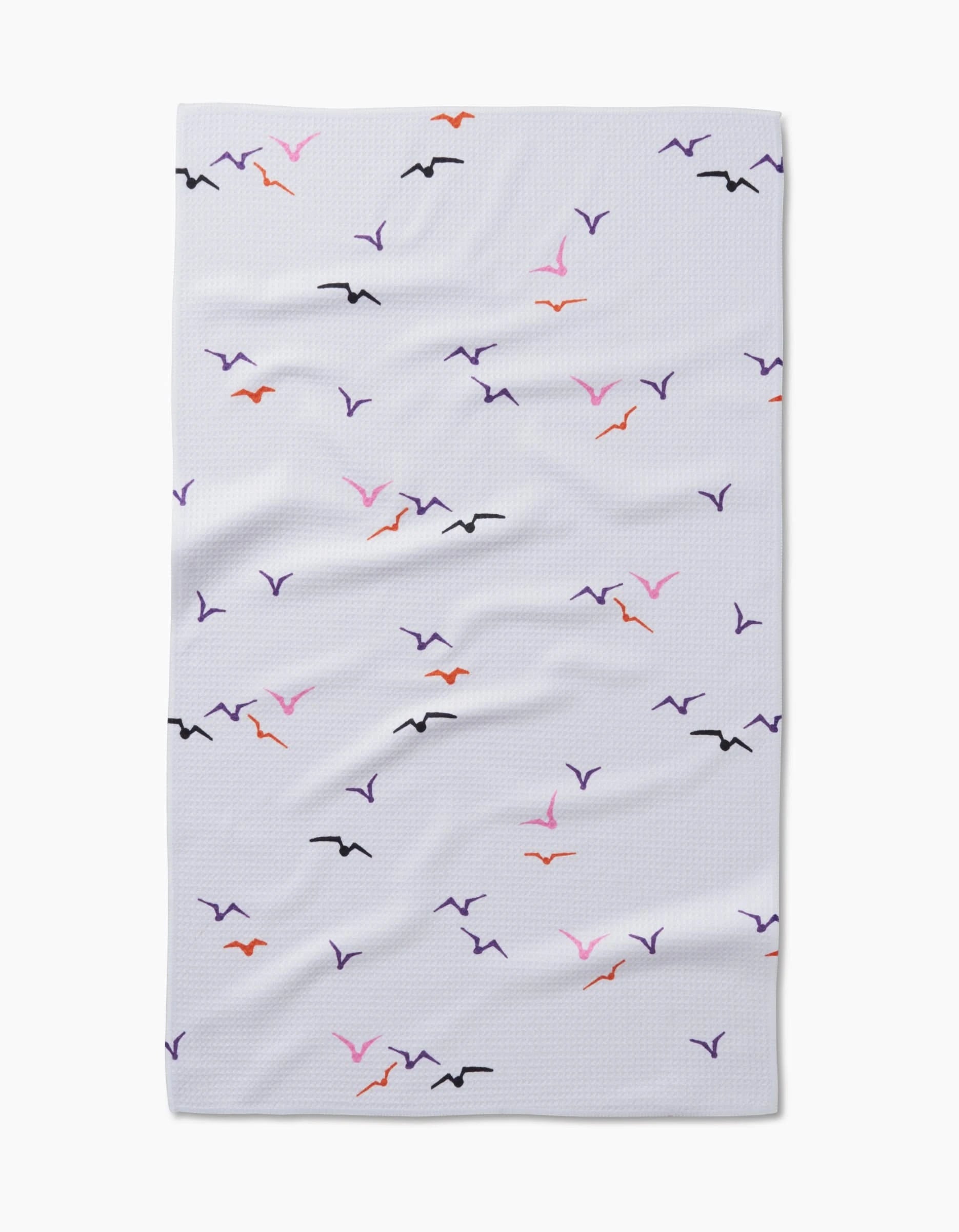 The Scattered Seagulls blanket by Ania Zwara Art is a white, textured throw made from recycled materials, featuring simple black, purple, orange, and pink seagull motifs scattered across the surface.