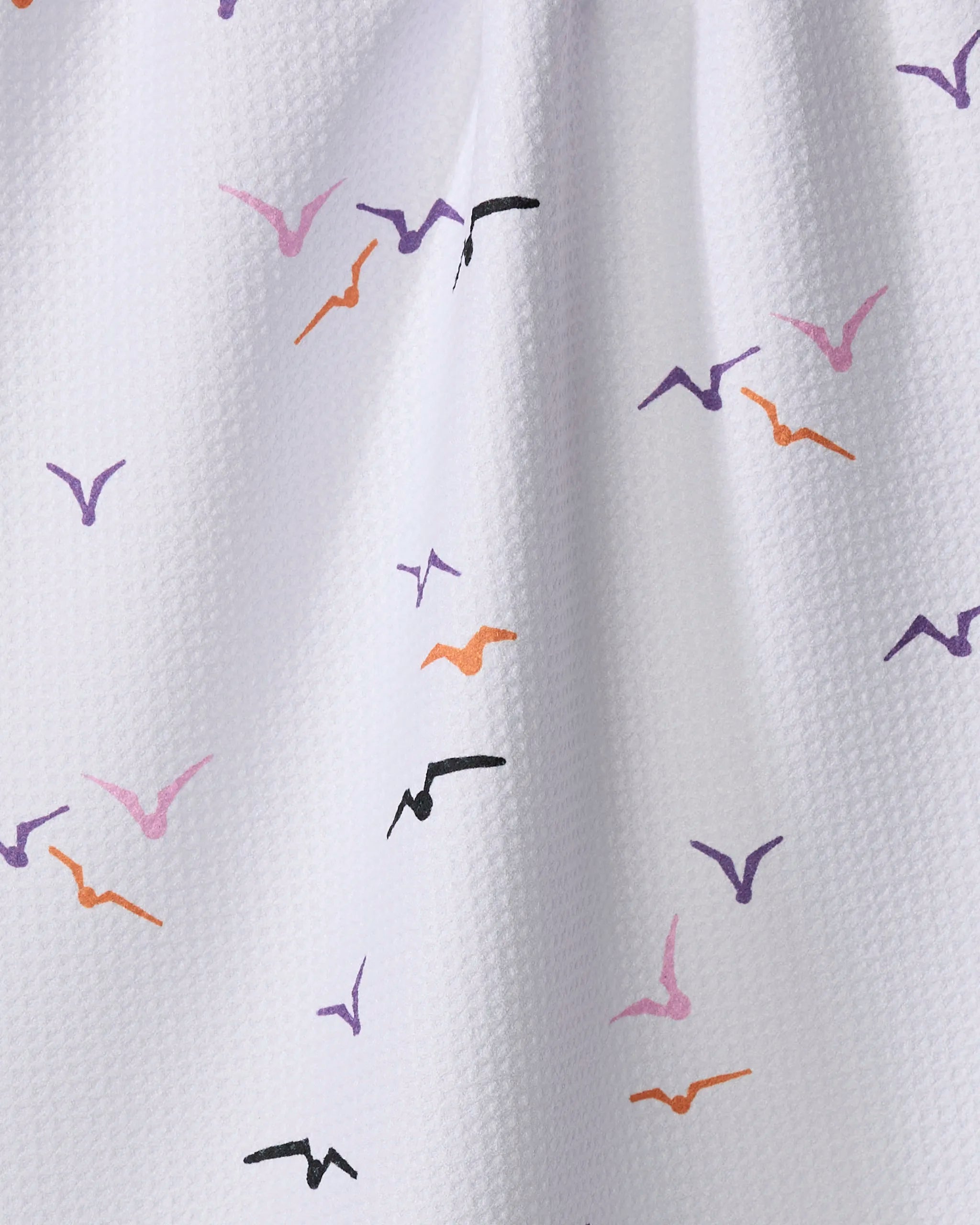 The Scattered Seagulls tea towel by Ania Zwara Art features white textured fabric with small purple, orange, and black stylized birds—a charming, ultra-absorbent addition for efficient dish drying in your kitchen.