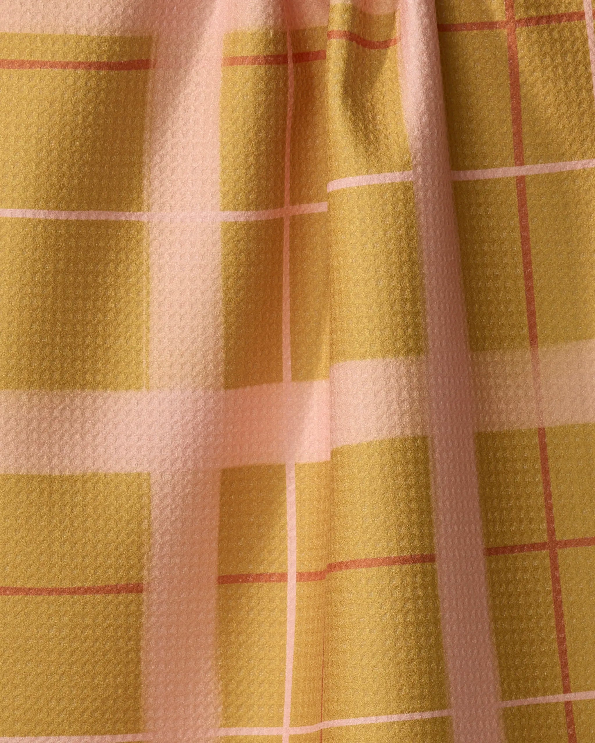 The Scotland Yard tea towel by Elisabeth Wing features yellow and pink plaid with thin red lines and a textured, slightly wrinkled surface—an absorbent dish towel perfect for brightening up any kitchen.