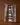 The Sedona kitchen towel by Geometry, featuring geometric blue, orange, white, and gray patterns, hangs from a string against a brown background.