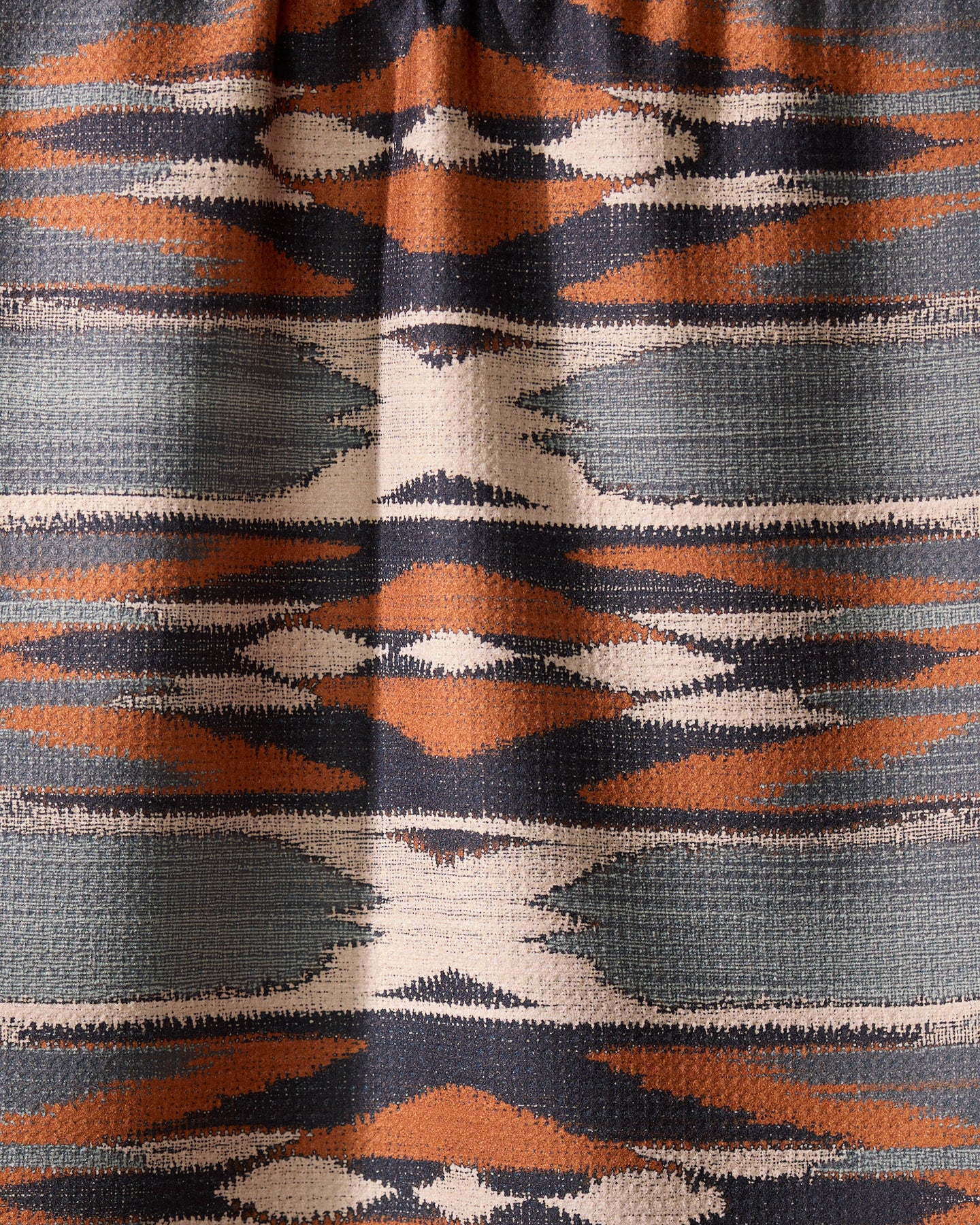 The Geometry Sedona tea towel features a geometric textile pattern with horizontal bands in orange, navy, white, and gray, showcasing symmetrical diamonds and zigzags—perfect for brightening your kitchen with its quick-drying design.
