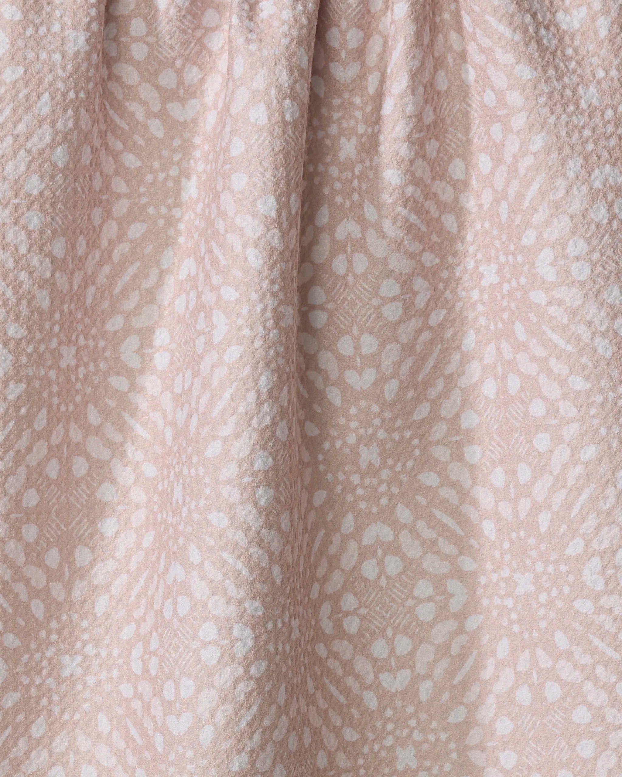 The Twig + Spark Seeds and Nuts Neutral tea towel features a soft, textured pale pink fabric with a gathered top and an intricate white pattern, offering absorbent performance for stylish everyday kitchen use.