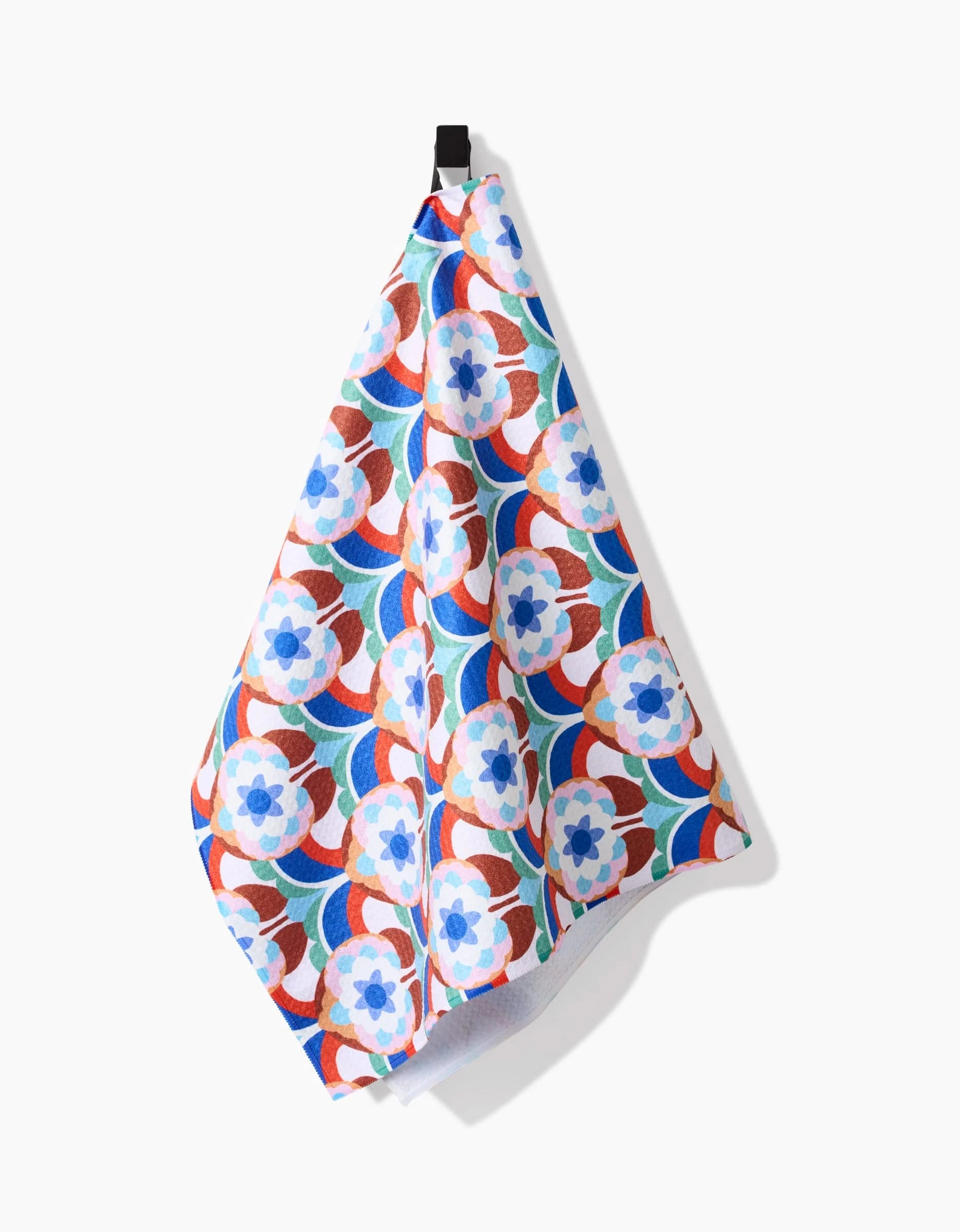 The Seventies Retro Flowers tea towel by Claire Iglesias features a blue, red, and white geometric floral pattern on ultra-absorbent recycled fabric and hangs from a black loop against a plain white background.