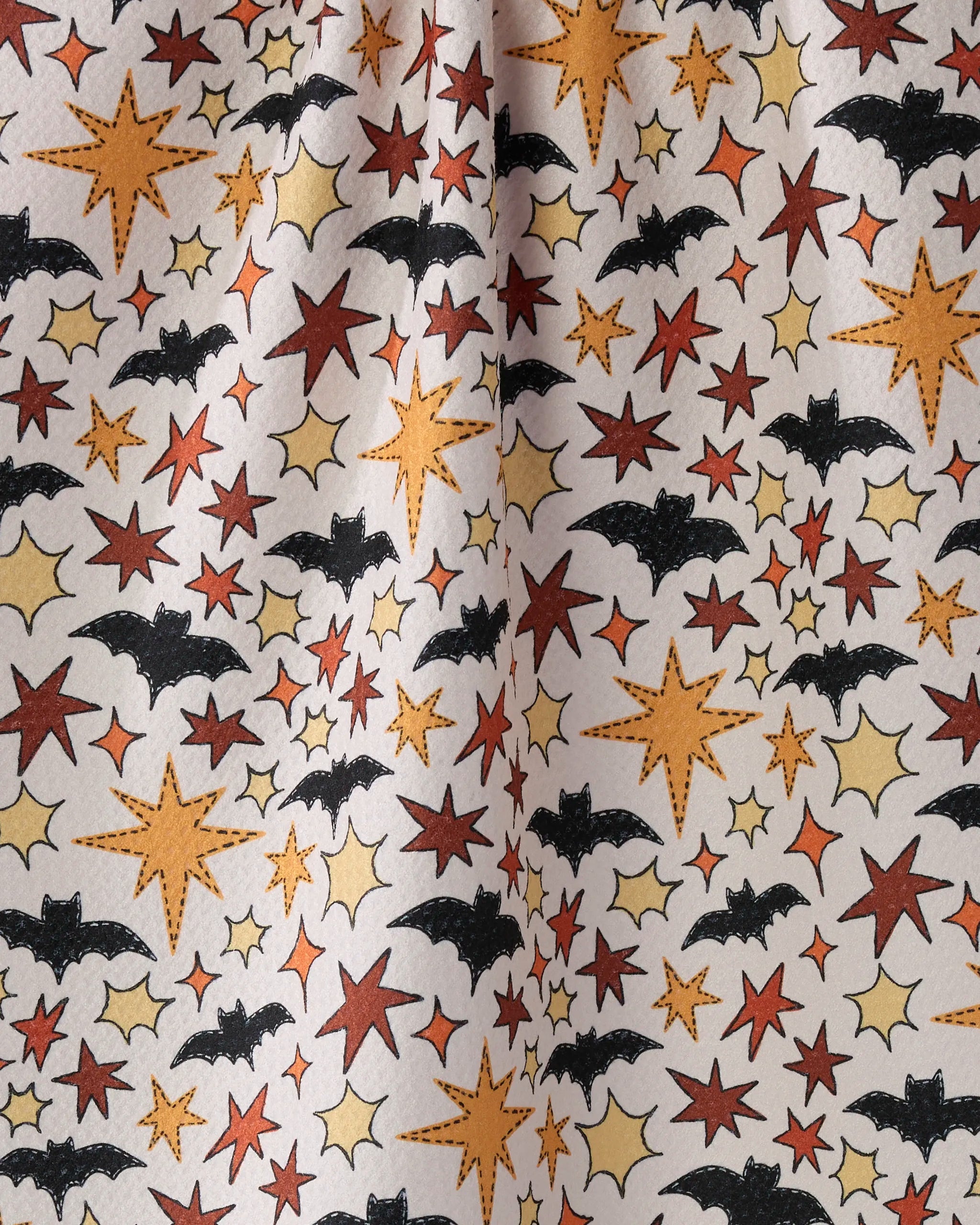 The Geometry Sew Batty kitchen towel displays black bats and yellow-orange stars of various sizes on a white background, made from recycled materials with a slightly wrinkled center.