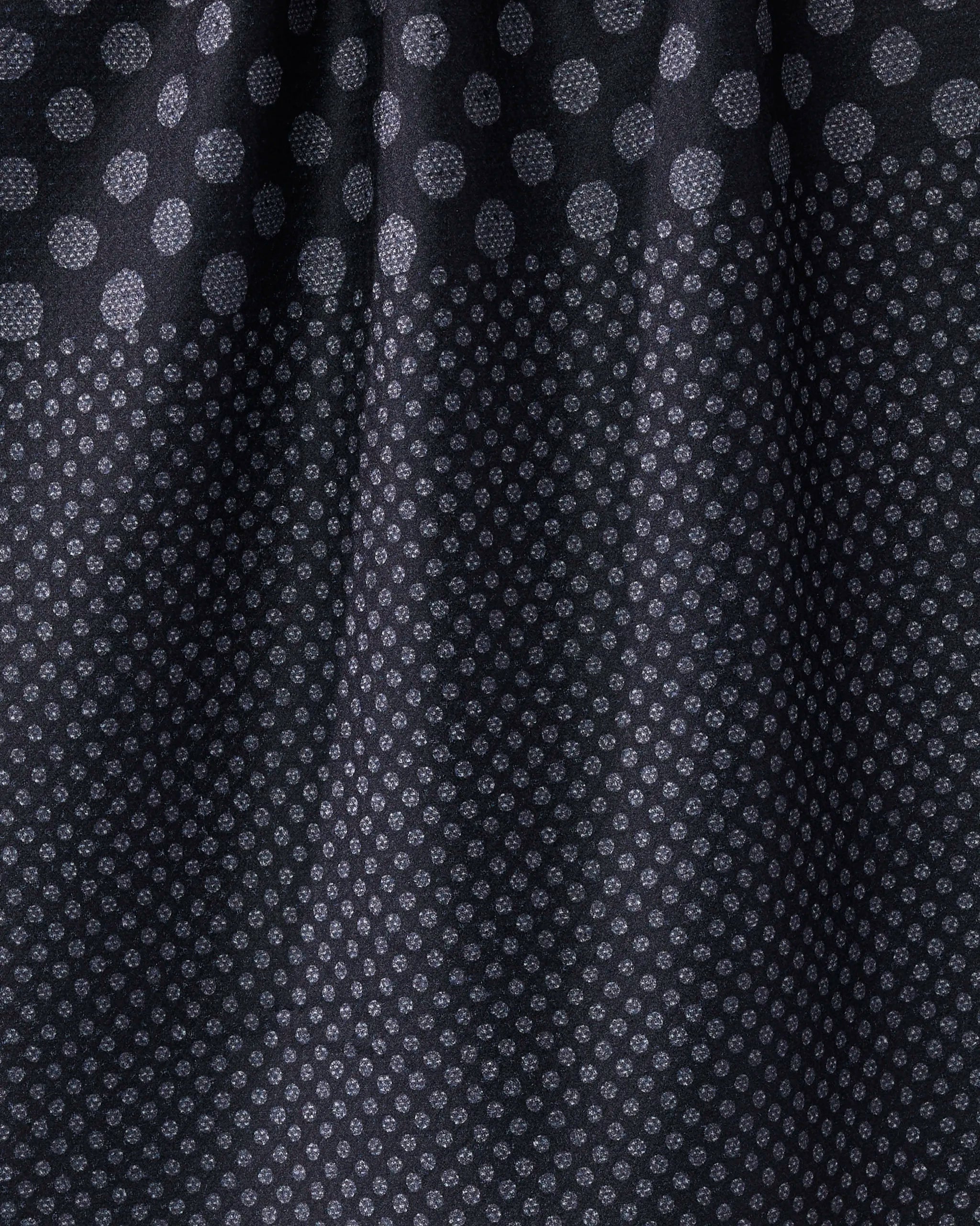 Close-up of Geometry's "Shadow Dot" tea towel: dark recycled fabric with large white polka dots on top, smaller dots below, and softly gathered folds.