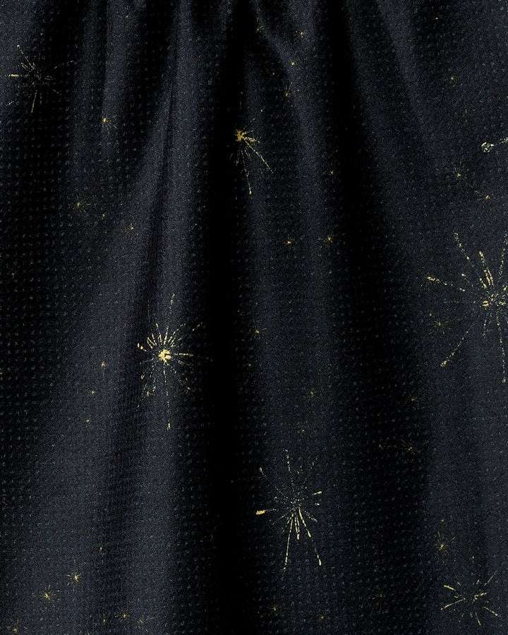 Introducing Shimmer Eve by Geometry: a dark fabric kitchen towel featuring subtle, scattered gold starburst patterns reminiscent of fireworks or stars. Made from recycled materials for an eco-friendly touch.