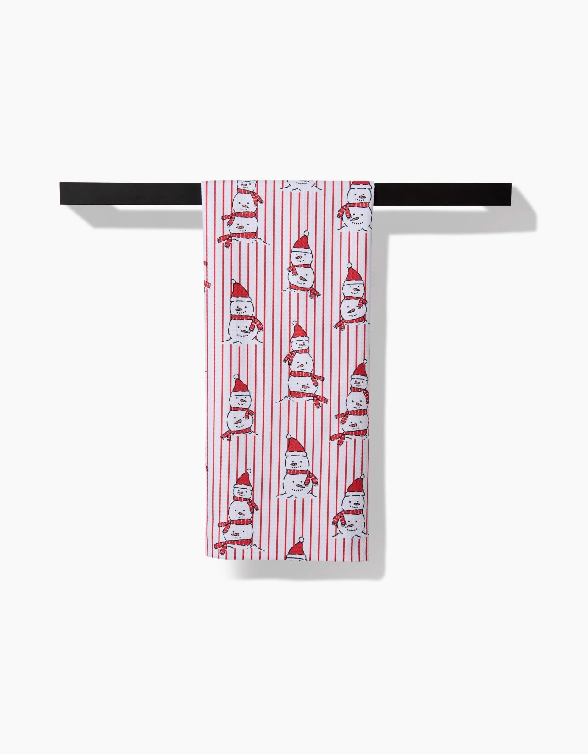 The Silly Snowman tea towel by Hufton Studio, made from recycled materials, features red vertical stripes and cartoon cats in red hats. It hangs on a black bar against a white background.