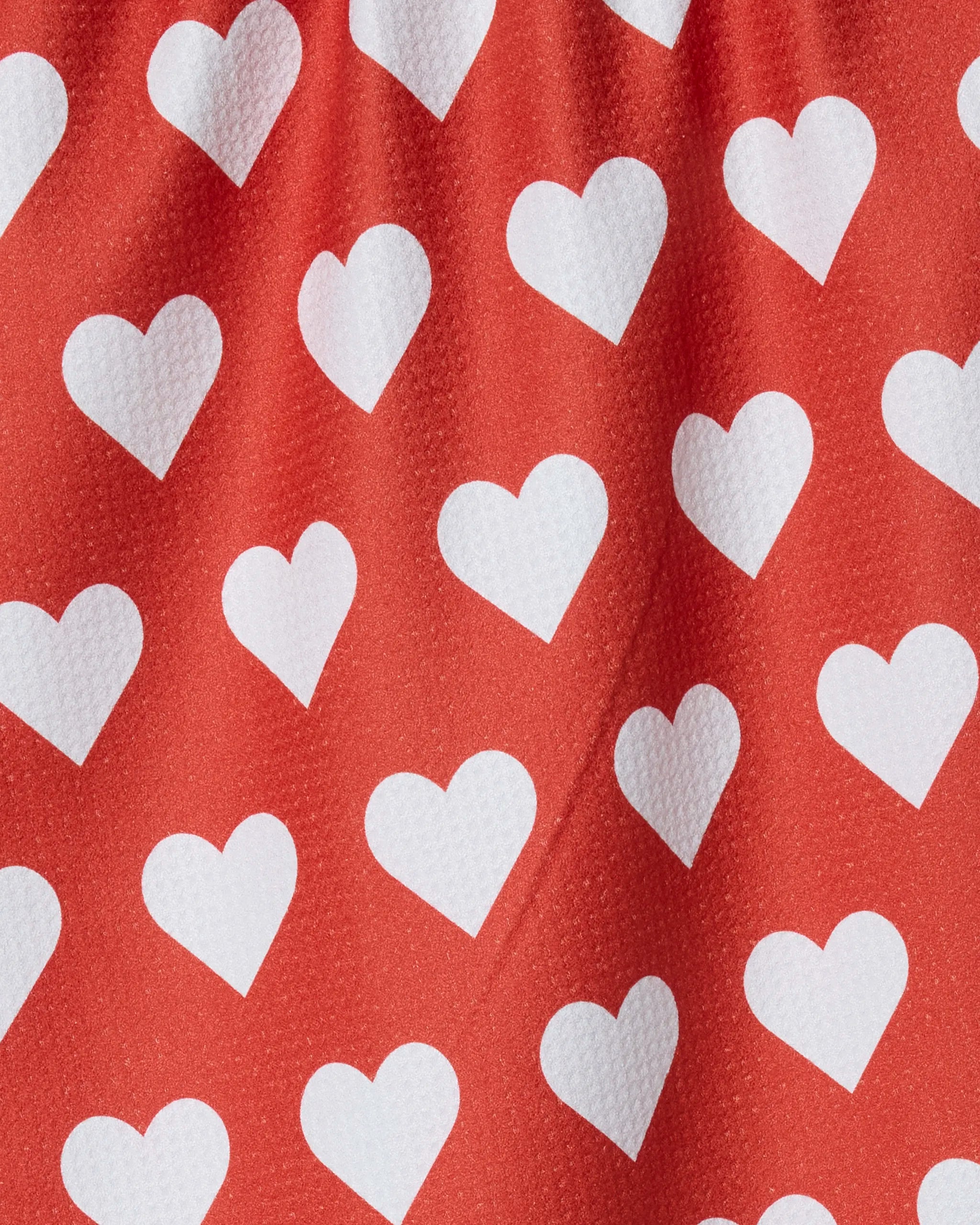The Geometry Simply Love dish towel features red fabric with evenly spaced white hearts. Its absorbent, slightly textured finish and gentle folds make it a charming and practical kitchen accessory.