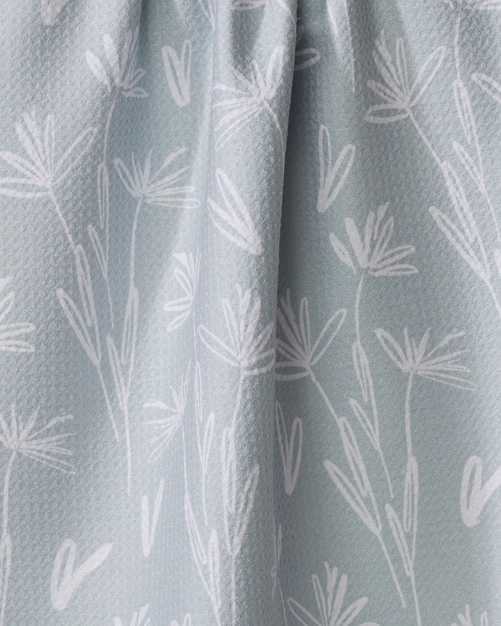 Close-up of the Toboggan Avenue Sketchbook Floral dish towel in light blue, featuring an absorbent textured fabric with white hand-drawn flowers and leaves, softly pleated at the top for style and function.