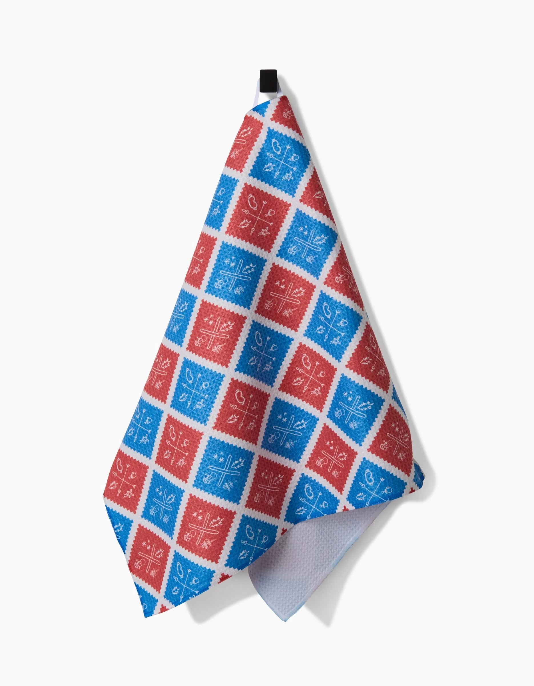 The Rosa Kichline Ski Patch is a quick-drying hanging tea towel with red and blue checks and white floral and geometric designs in each square, shown against a plain white background.