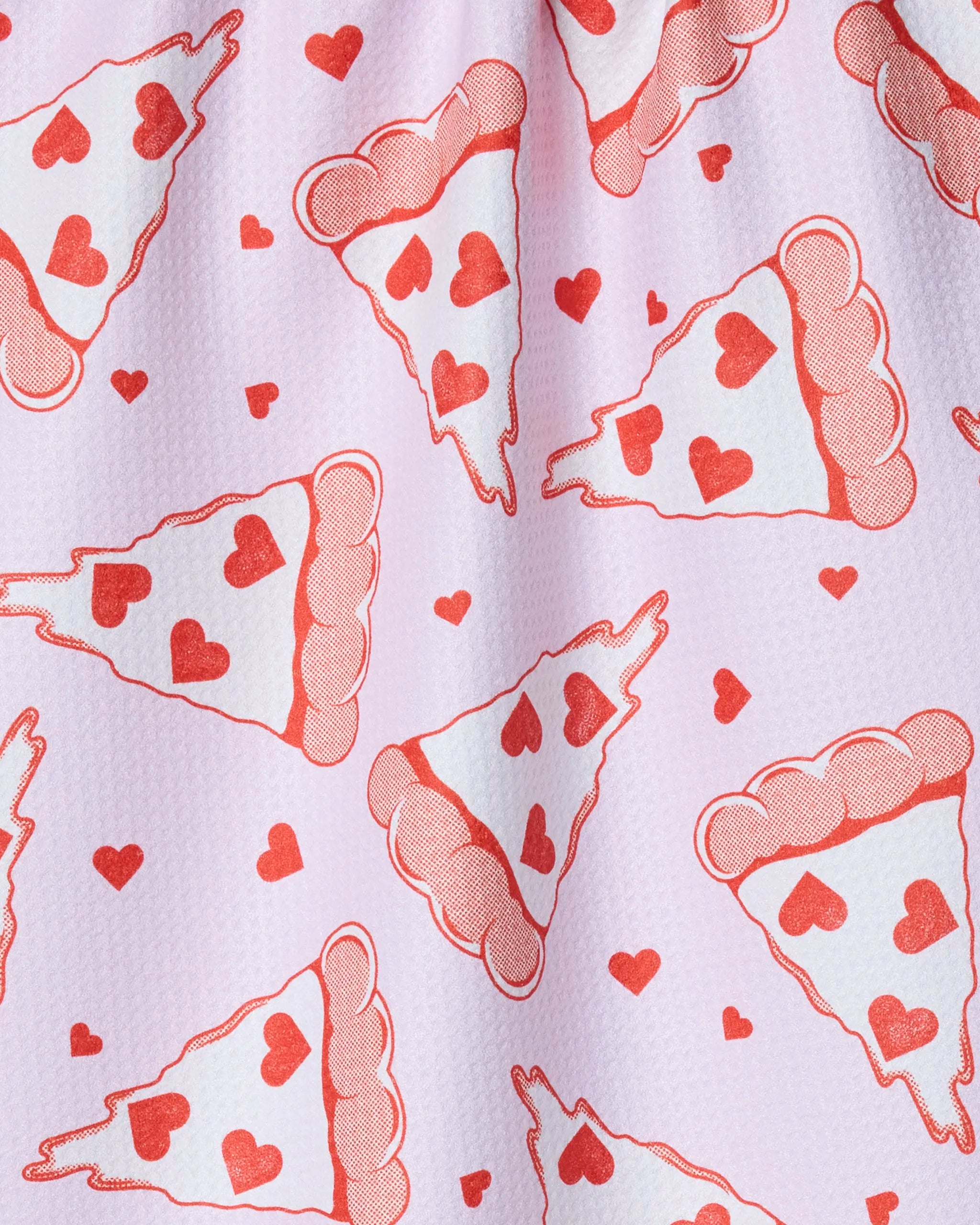 The Geometry "Slice of Heaven" towel is pink, quick-drying, and features red pizza slices with heart-shaped pepperoni and small red hearts for a playful, whimsical touch.