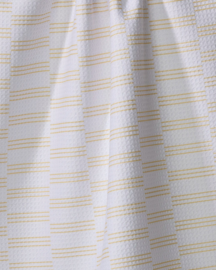 The Buy Guide's "Small Stripe - Yellow" tea towel features white textured fabric with thin yellow stripes, made from recycled materials. Ultra-absorbent and soft, it brings subtle elegance and sustainability to your kitchen.
