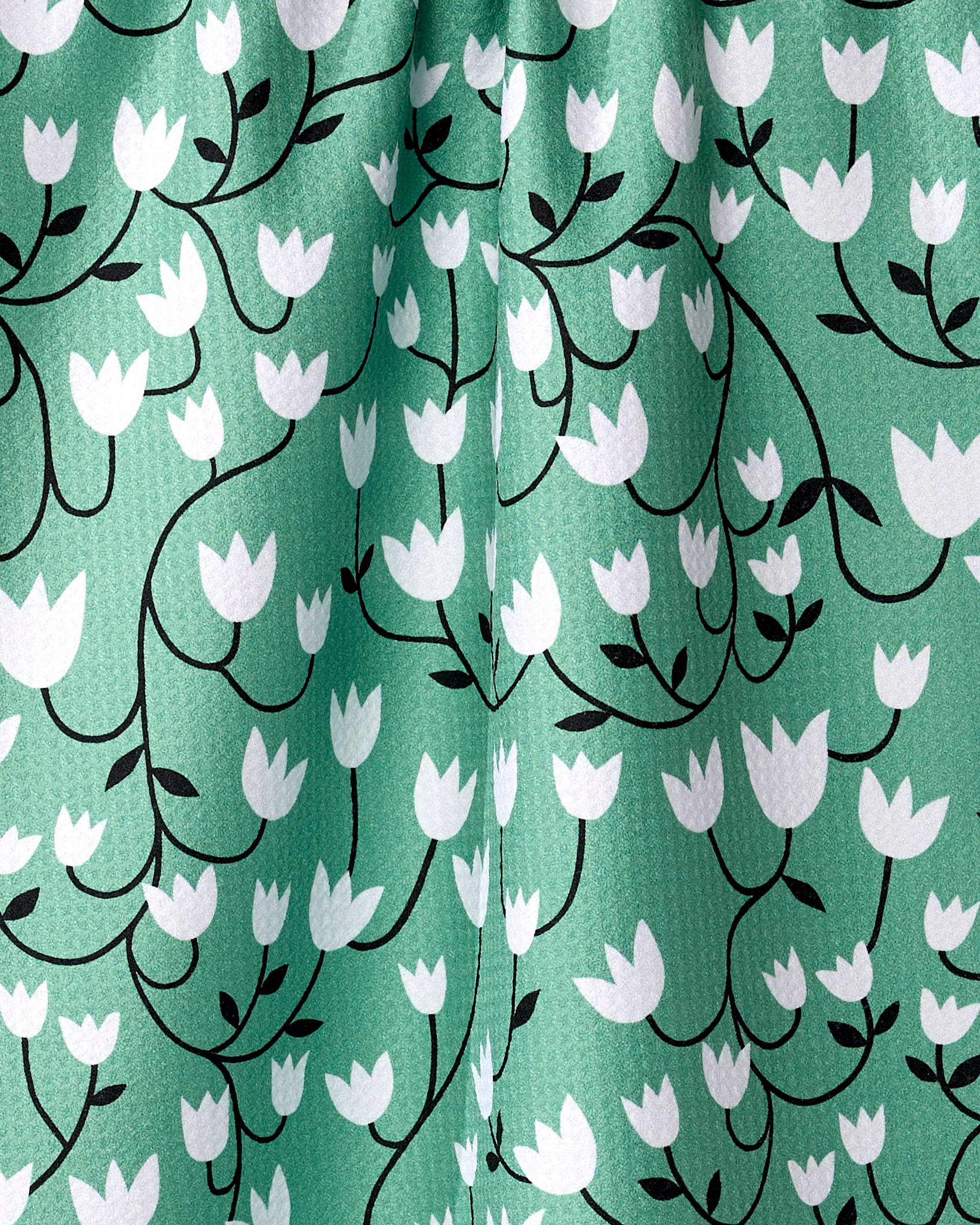 A close-up of Snowdrop by Rachel Parker shows green recycled fabric with a textured surface, featuring white tulip-like flowers and black stems. The kitchen towel displays slight folds in its eco-friendly design.