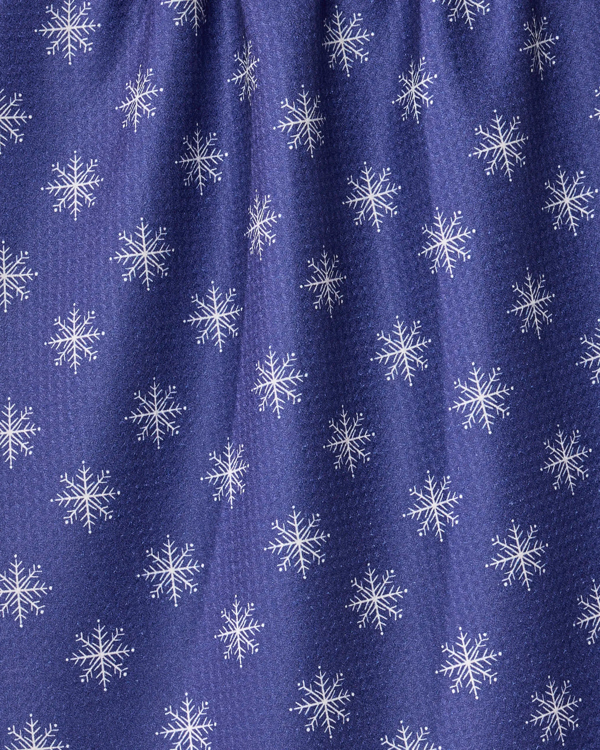 The Geometry Snowy tea towel features a blue fabric adorned with a repeating pattern of white snowflakes. Crafted to be ultra-absorbent, this towel has gentle gathering at the top, which creates delicate folds and subtle shadows.