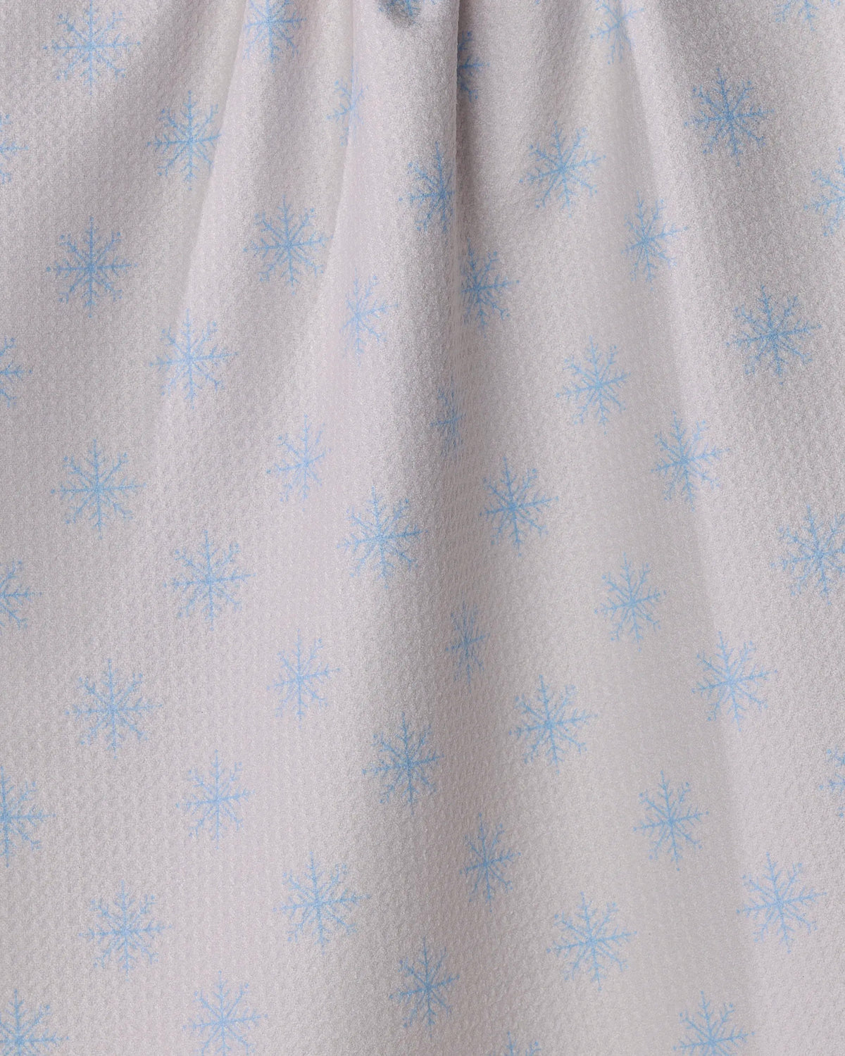 Close-up of Geometry’s Snowy tea towel, crafted from recycled materials and featuring a light texture with a repeating pattern of small blue snowflakes evenly spaced across its ultra-absorbent surface.