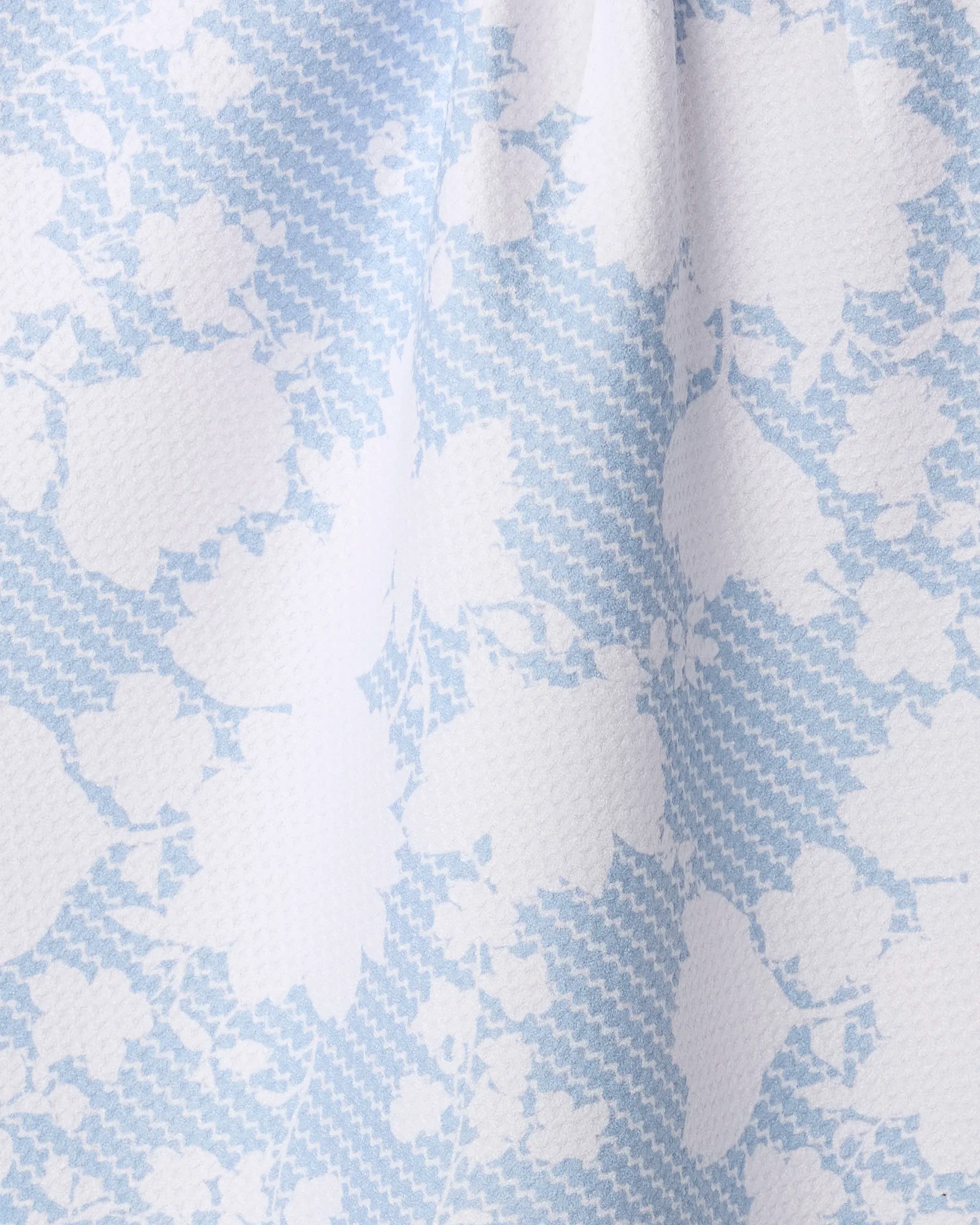 Close-up of Geometry’s Soft Bloom tea towel, made from recycled materials. White floral patterns pop over a blue houndstooth background in this ultra-absorbent, textured fabric.