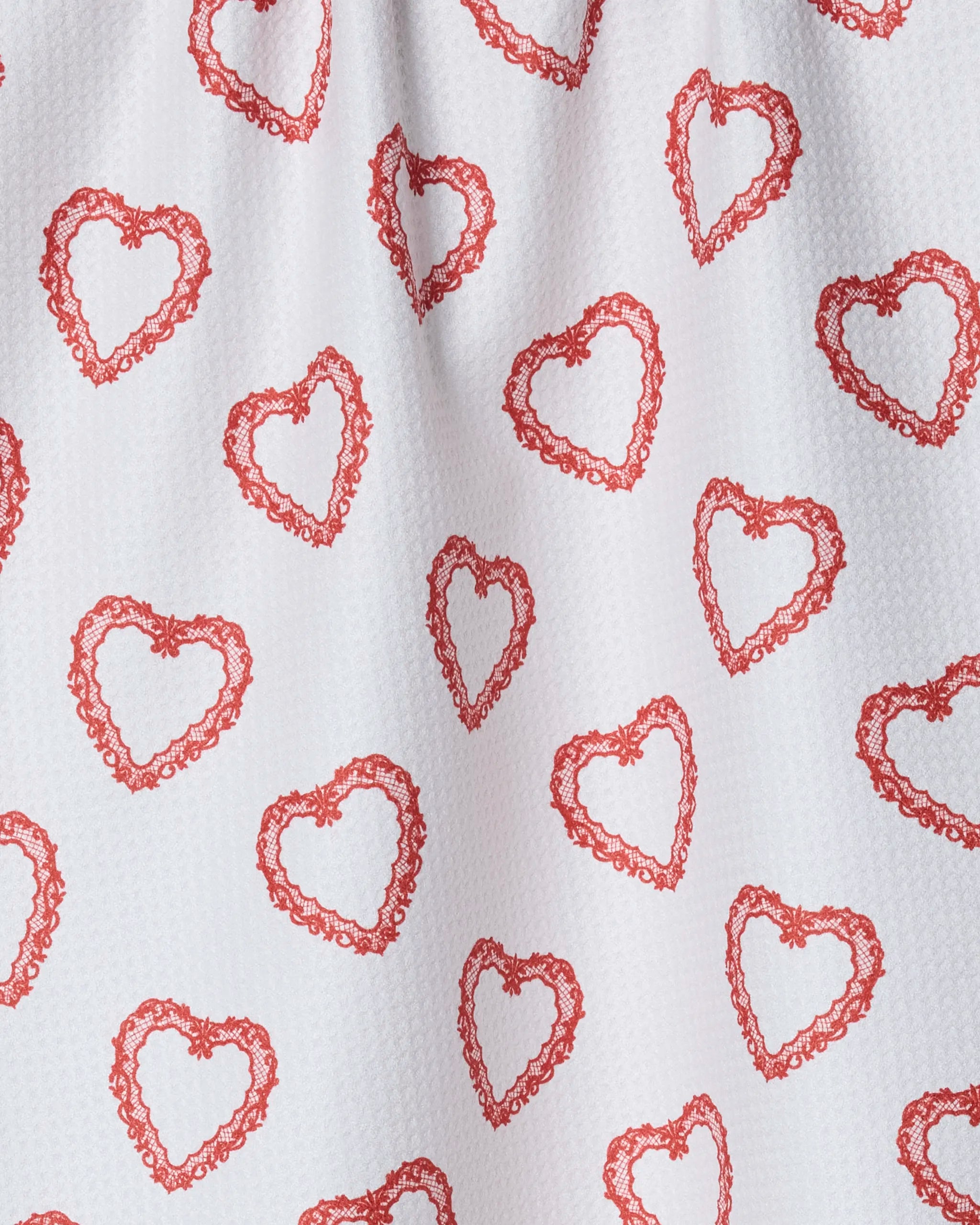 The Geometry Soft Heart tea towel features a textured white fabric with evenly spaced red, lace-like heart outlines. Made from quick-drying recycled materials, this towel combines eco-friendly function with charming design.