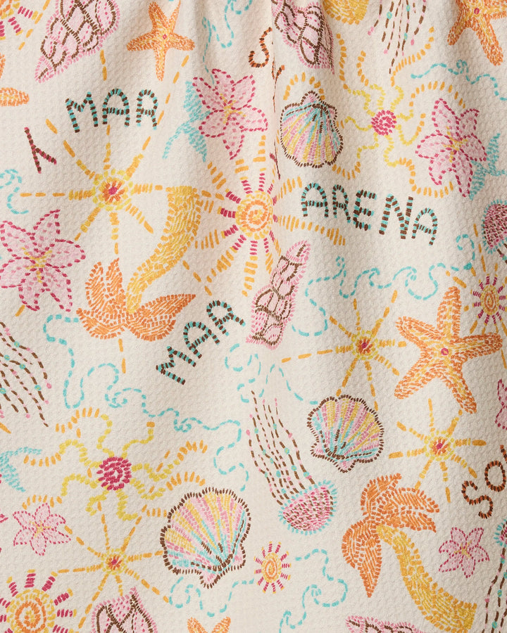The Sol y Mar kitchen towel by Geometry features colorful recycled fabric embroidered with seashells, starfish, flowers, and “MAR” and “ARENA,” creating a cheerful beach-themed design—perfect for adding unique style to your kitchen.