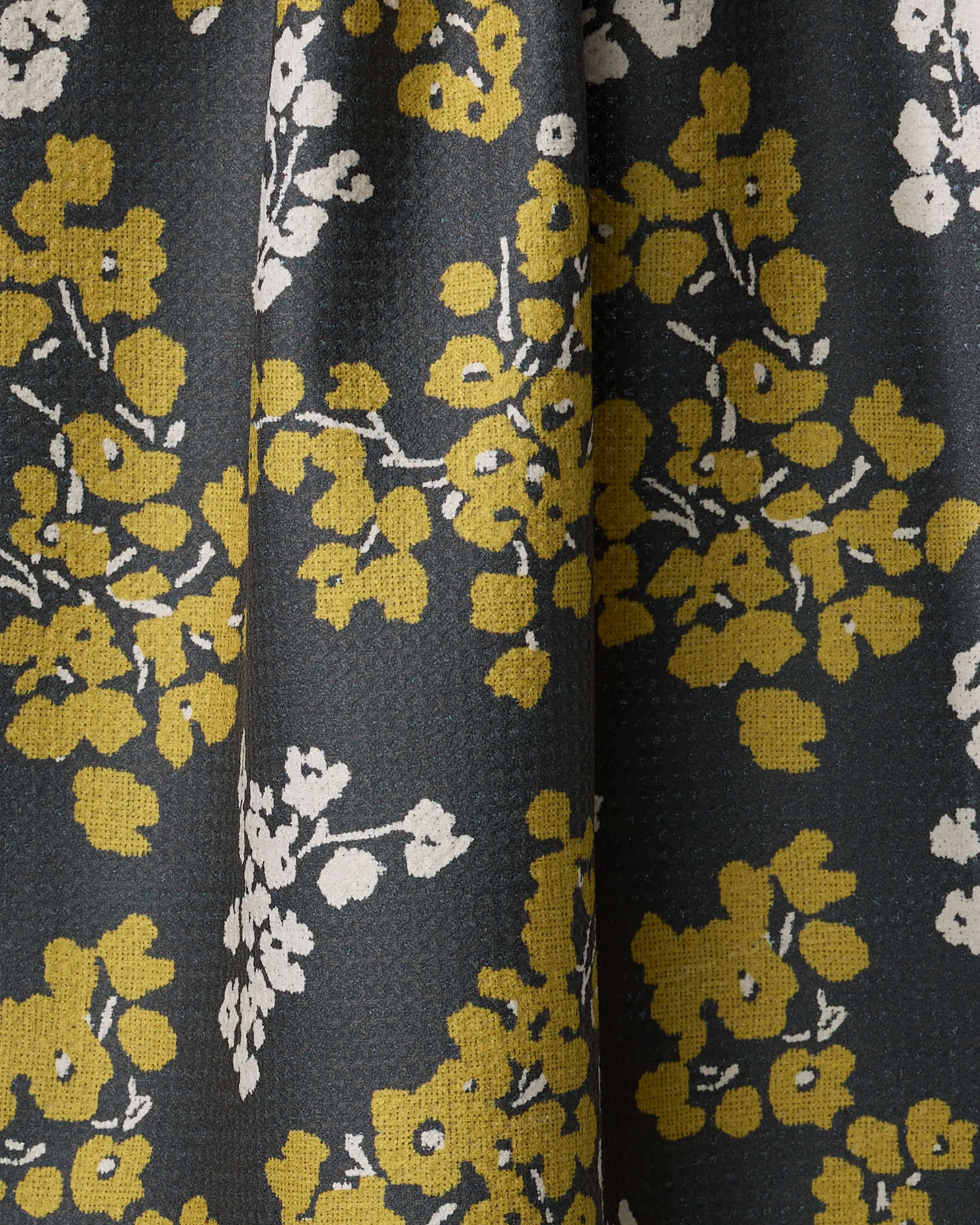 The Sonnet Ember tea towel by Geometry features yellow and white floral clusters and branches on dark fabric. Made from recycled materials, it’s ultra-absorbent with gentle folds and a subtly textured surface.