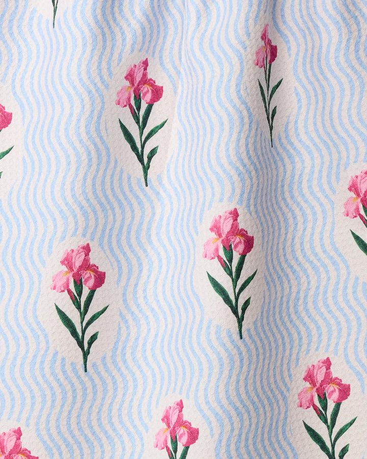 Spatial Bloom by Geometry is a fabric tea towel with wavy blue and white stripes and repeating pink flowers with green stems and leaves, made from recycled materials.