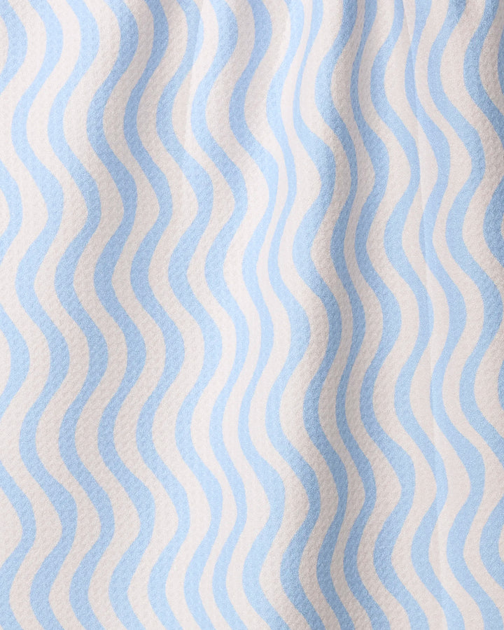 A close-up of Geometry’s Spatial tea towel shows its quick-drying, recycled fabric with wavy blue and white stripes and a textured, slightly wrinkled surface.