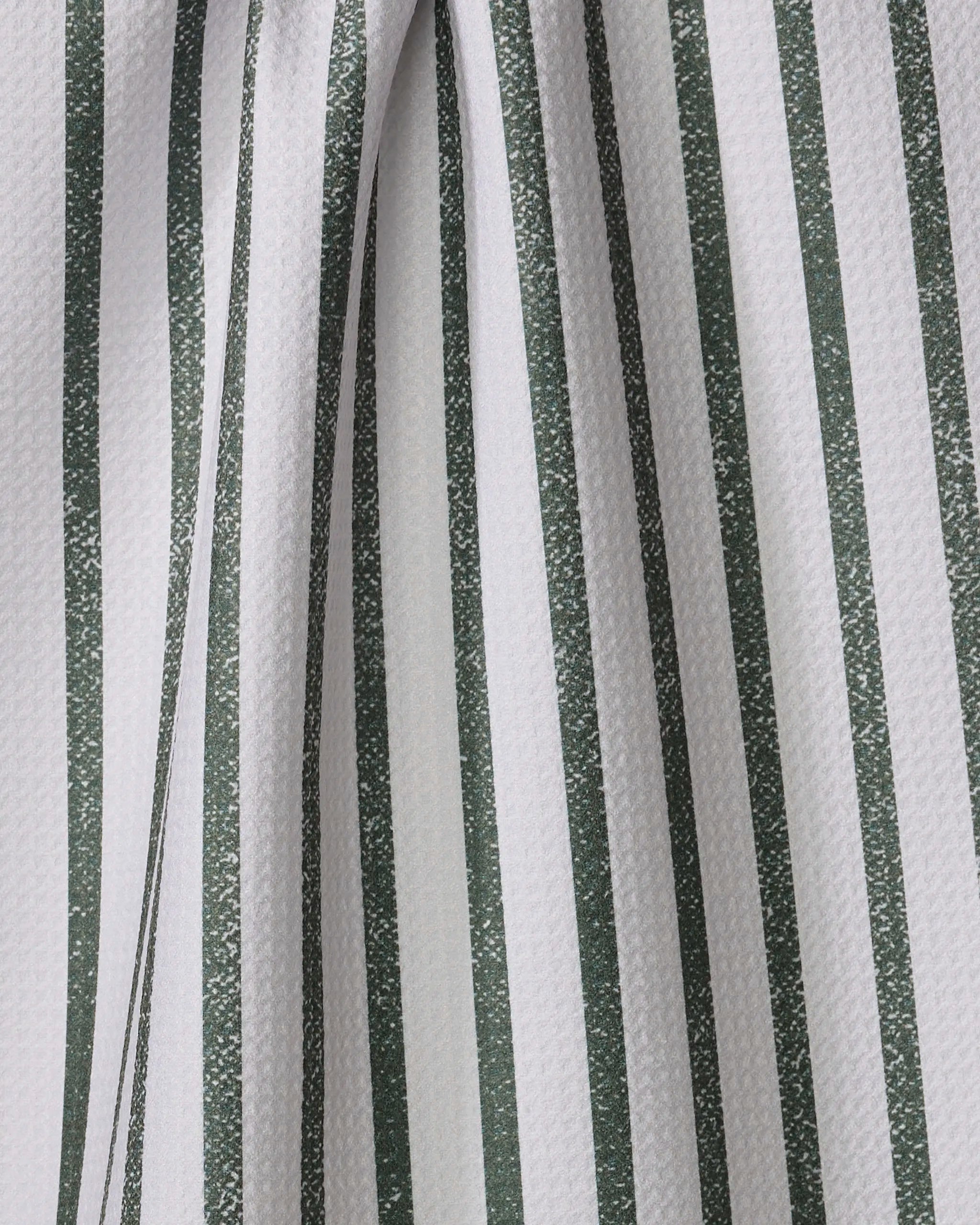Close-up of the Becki Owens Spearmint tea towel, featuring textured white fabric with vertical green stripes. The slightly folded material creates soft curves and subtle shadows along the striped pattern.