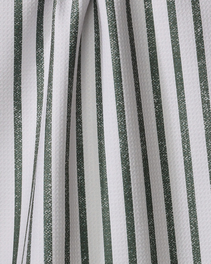 Close-up of the Becki Owens Spearmint tea towel, featuring textured white fabric with vertical green stripes. The slightly folded material creates soft curves and subtle shadows along the striped pattern.