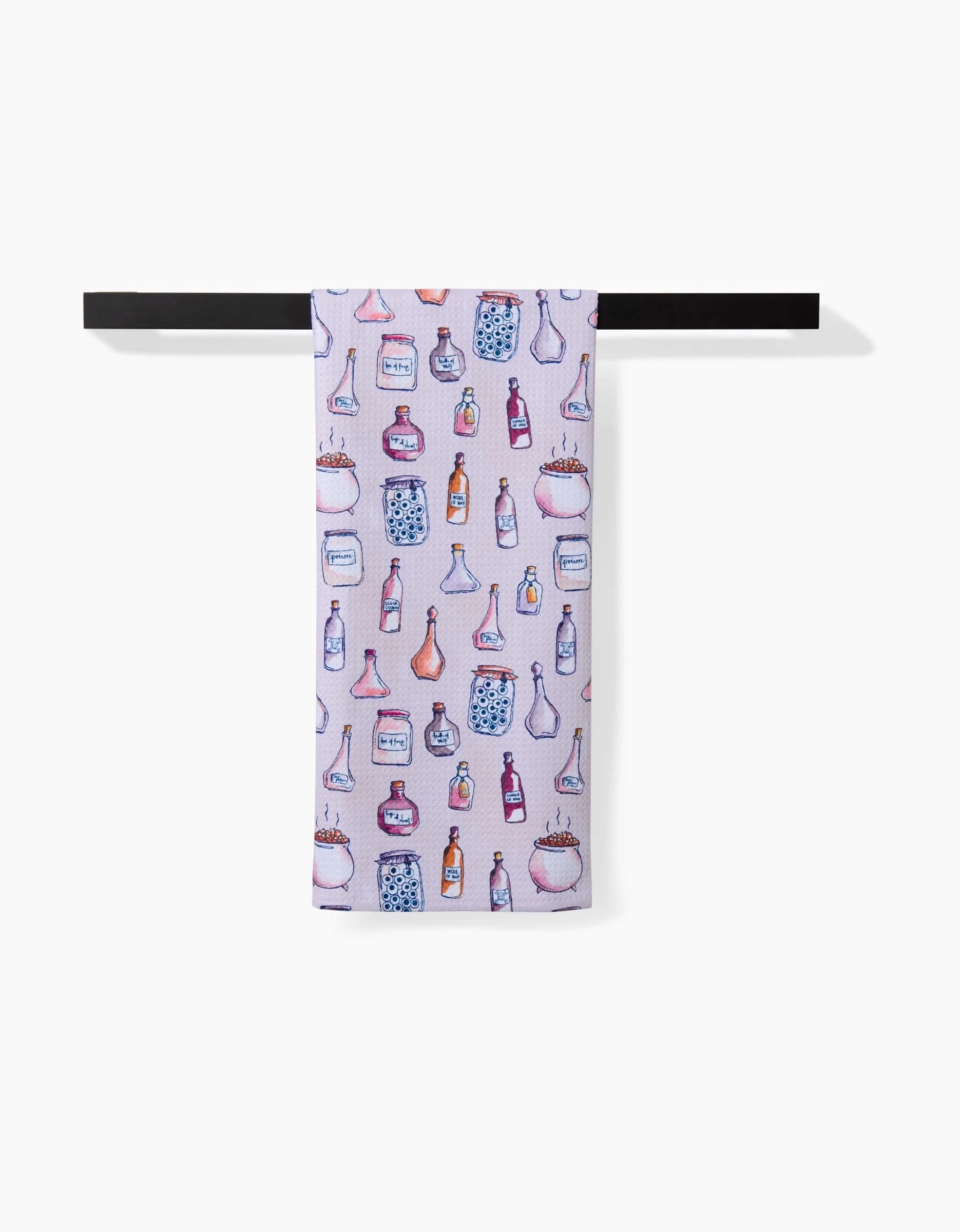 The Spells Potions tea towel by Maayan Alper-Swan hangs on a black bar, adorned with colorful illustrations of bottles and jars in pink, blue, and purple tones.
