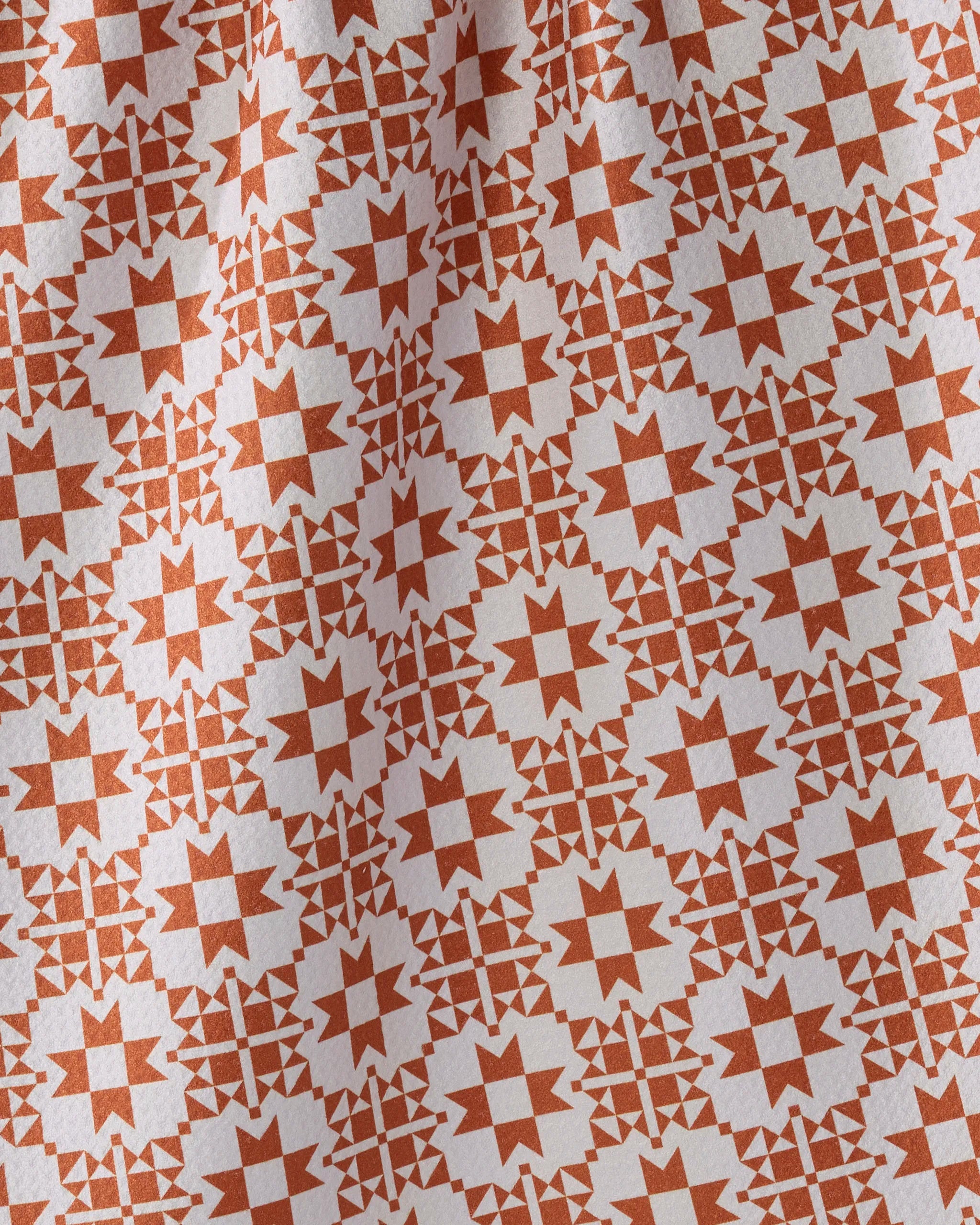 Spellwork by Geometry features red star and cross patterns on white, creating a quilt-like, symmetrical design with visible folds—ideal as an absorbent kitchen towel made from recycled materials.