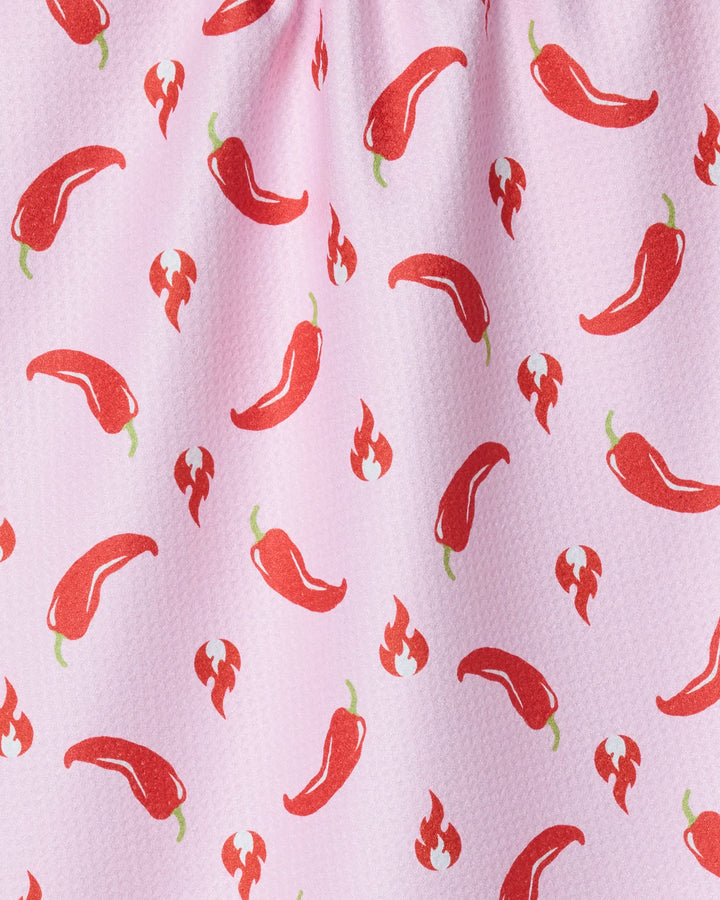 The Geometry Spicy tea towel features a pink background with a repeating pattern of red chili peppers and flame icons. Its slightly visible texture and quick-drying fabric make it perfect for daily kitchen use.