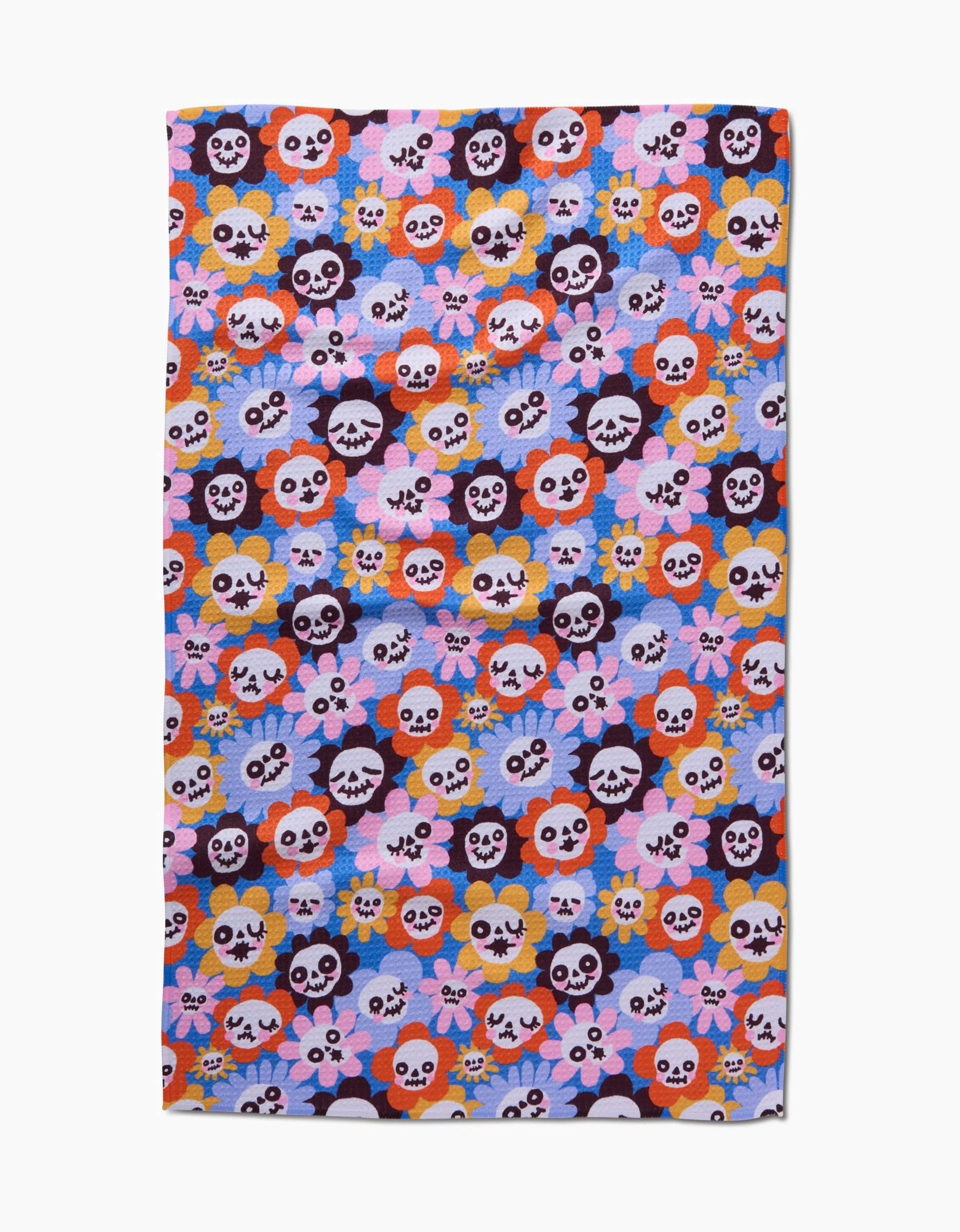 The So Lazo Spooky Bouquet tea towel features cartoon skulls and colorful flowers in red, orange, yellow, pink, purple, and blue on light lavender. Made from quick-drying recycled materials.