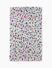 The Spot tea towel by Rachel Parker features a white, ultra-absorbent fabric with scattered black, pink, blue, orange, green, and purple spots. Its plain background highlights the lively pattern on this slightly wrinkled kitchen accessory.