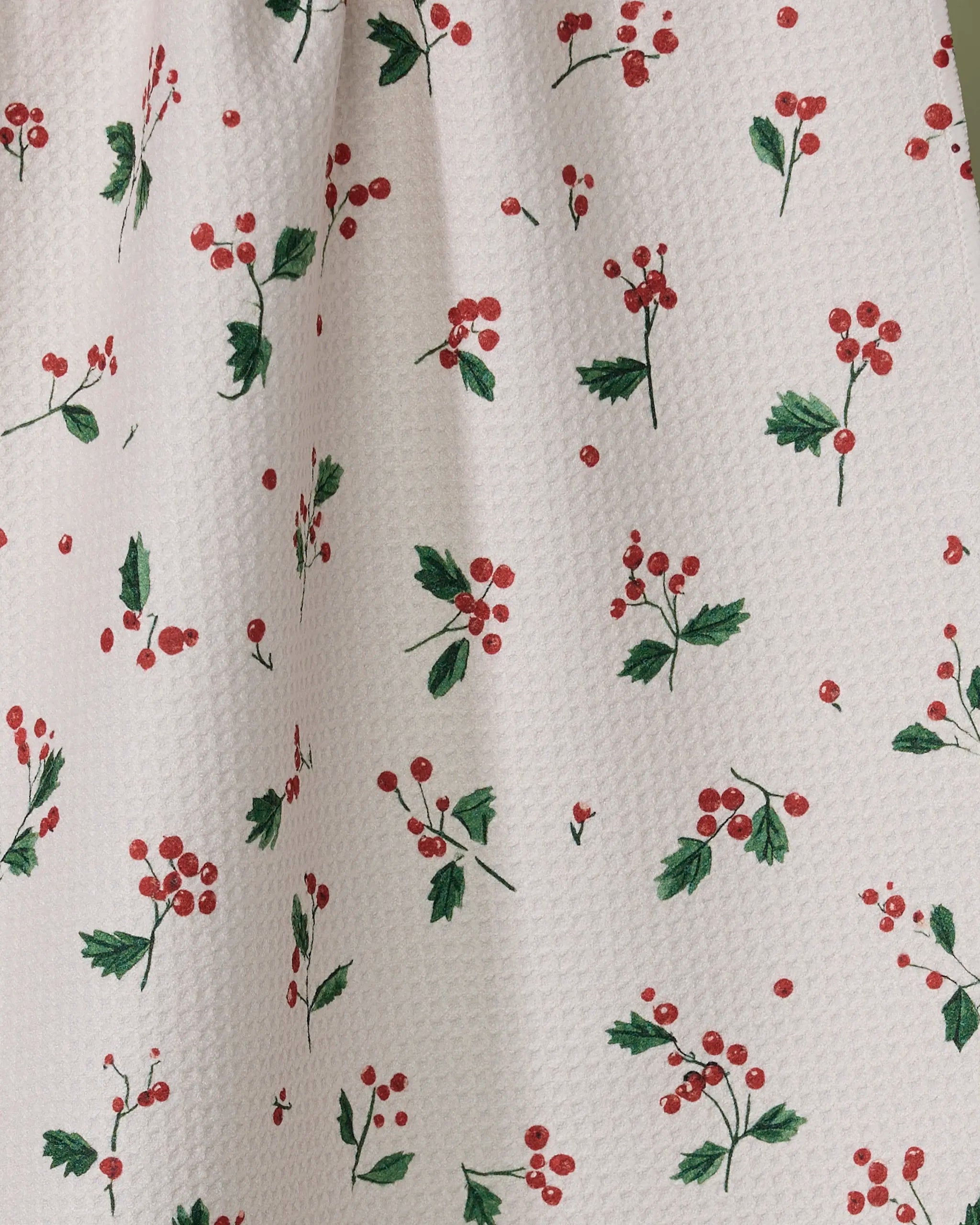 The Geometry Sprig tea towel features a white textured fabric made from recycled materials, printed with red berry and green leaf clusters in a charming, repeating pattern.
