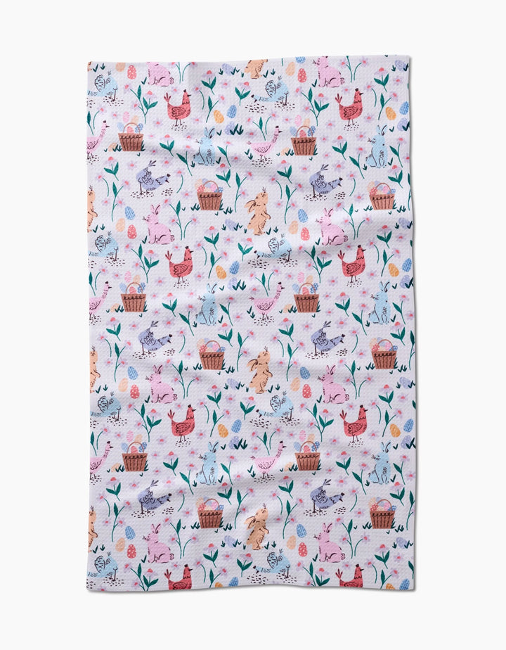 The Spring Bunnies tea towel by Charlie Rowan Designs features a colorful pastel pattern of chickens, eggs, flowers, leaves, and baskets on white. Made from ultra-absorbent recycled materials for style and sustainability.