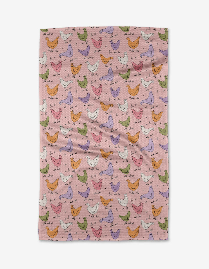 The Kayla Ann Spring Chickens tea towel features a pink background with colorful chickens in green, orange, purple, and white. Ultra-absorbent and slightly wrinkled for charm, it adds a playful touch to your kitchen.