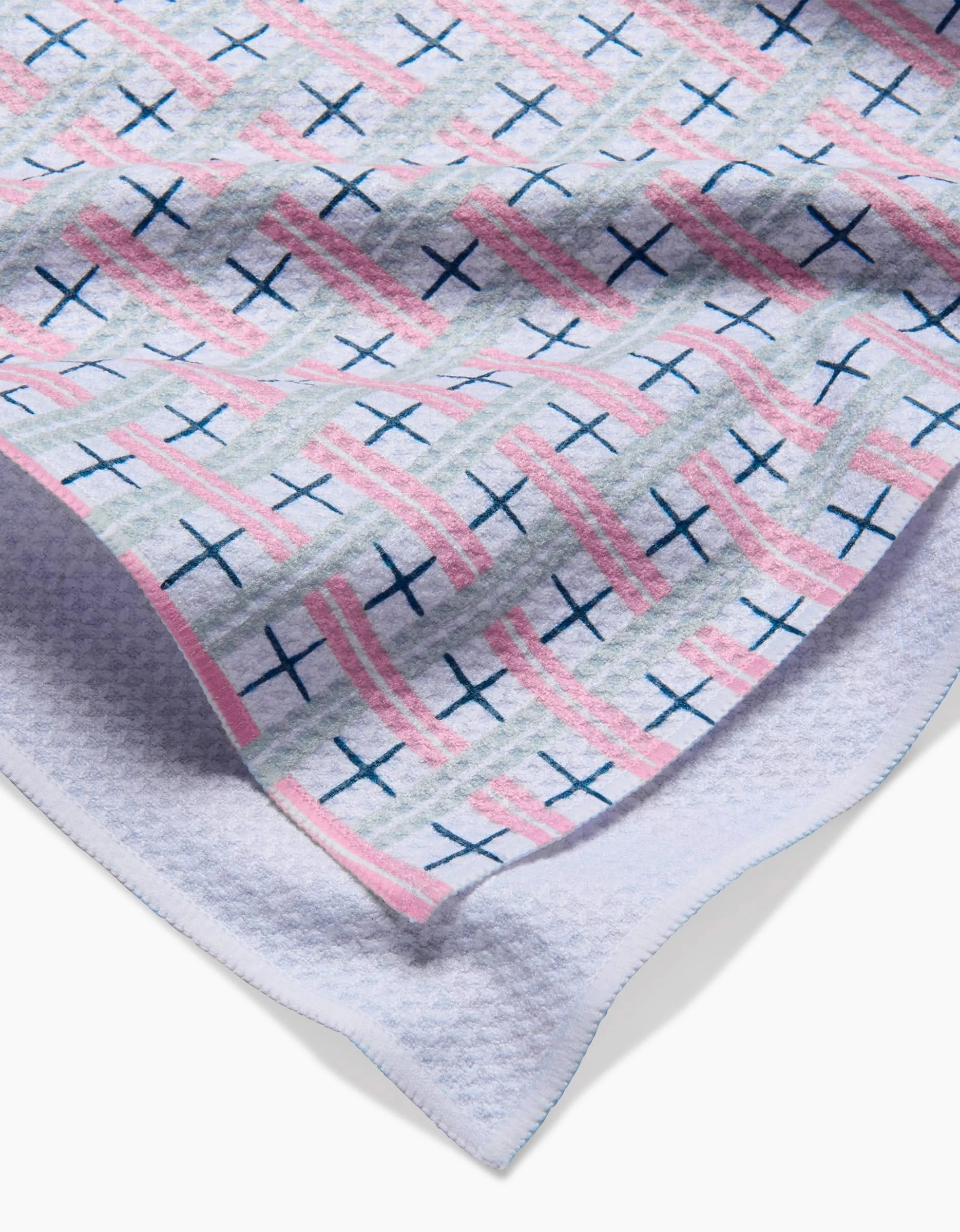 A close-up of the Spring Cottage Plaid by Hufton Studio, a folded hospital blanket featuring pink and blue stripes with navy cross accents, crafted from Geoweave fabric with a textured white underside, similar in quality to a Geometry House Tea Towel.