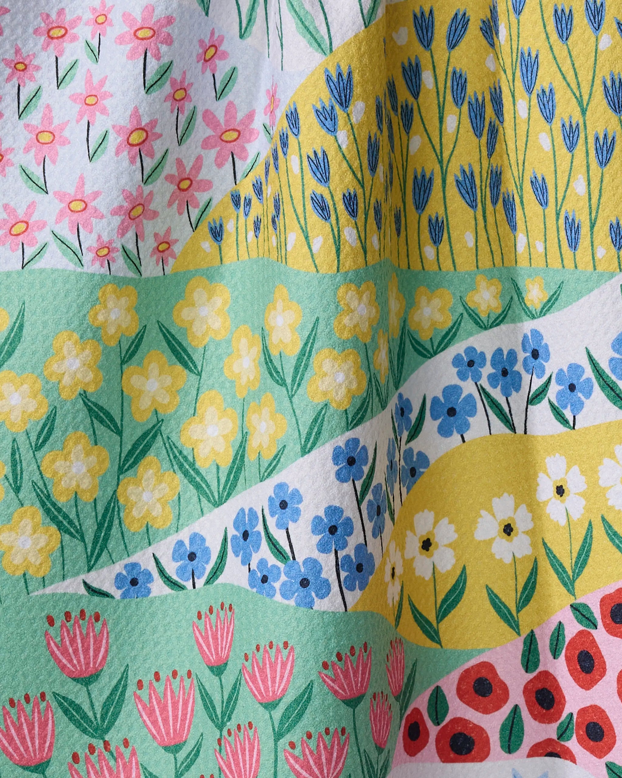 The Spring Fields kitchen towel by Ceyda Alasar features wavy stripes in pink, yellow, blue, and red with hand-drawn florals on recycled fabric for a cheerful, vibrant look.