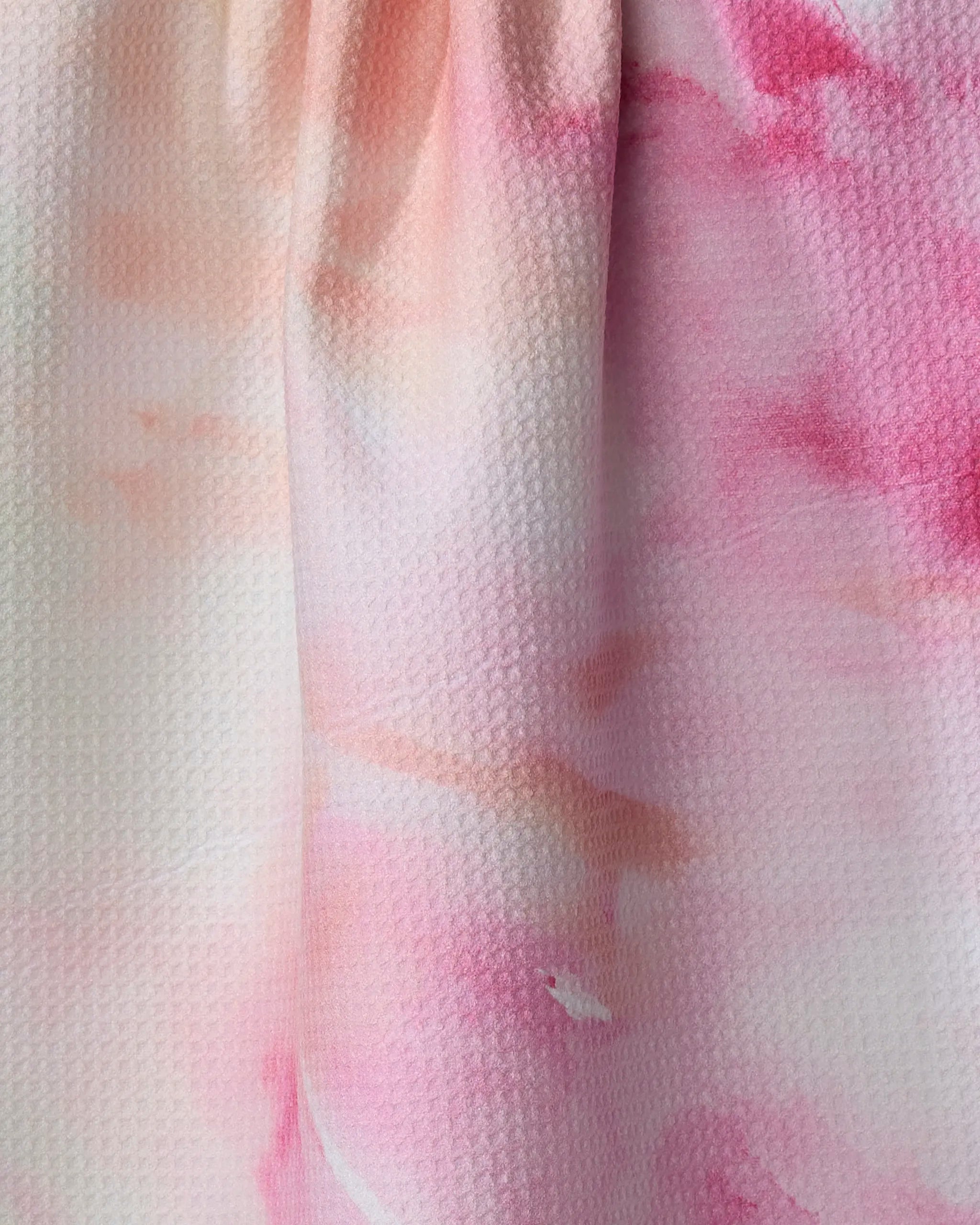 Close-up of the Stefanie Bales Spring Garden towel, ultra-absorbent and made from recycled materials. Features a soft, watercolor-inspired pattern in pink, peach, and white with delicate folds for a dreamy look.