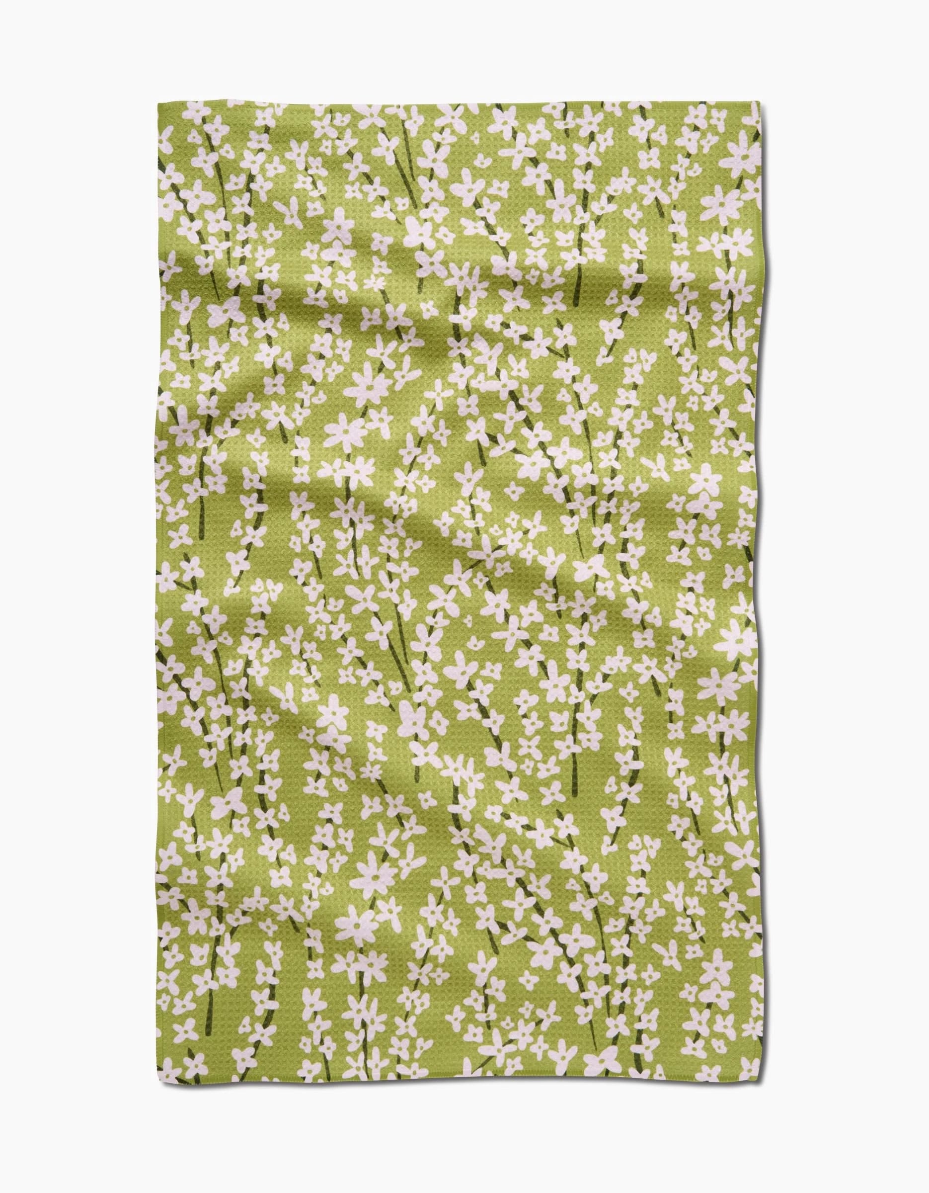 The Kayla Ann Spring Green Forsythia towel features ultra-absorbent Geoweave fabric with a pattern of small white flowers and branches, shown slightly wrinkled on a white background.