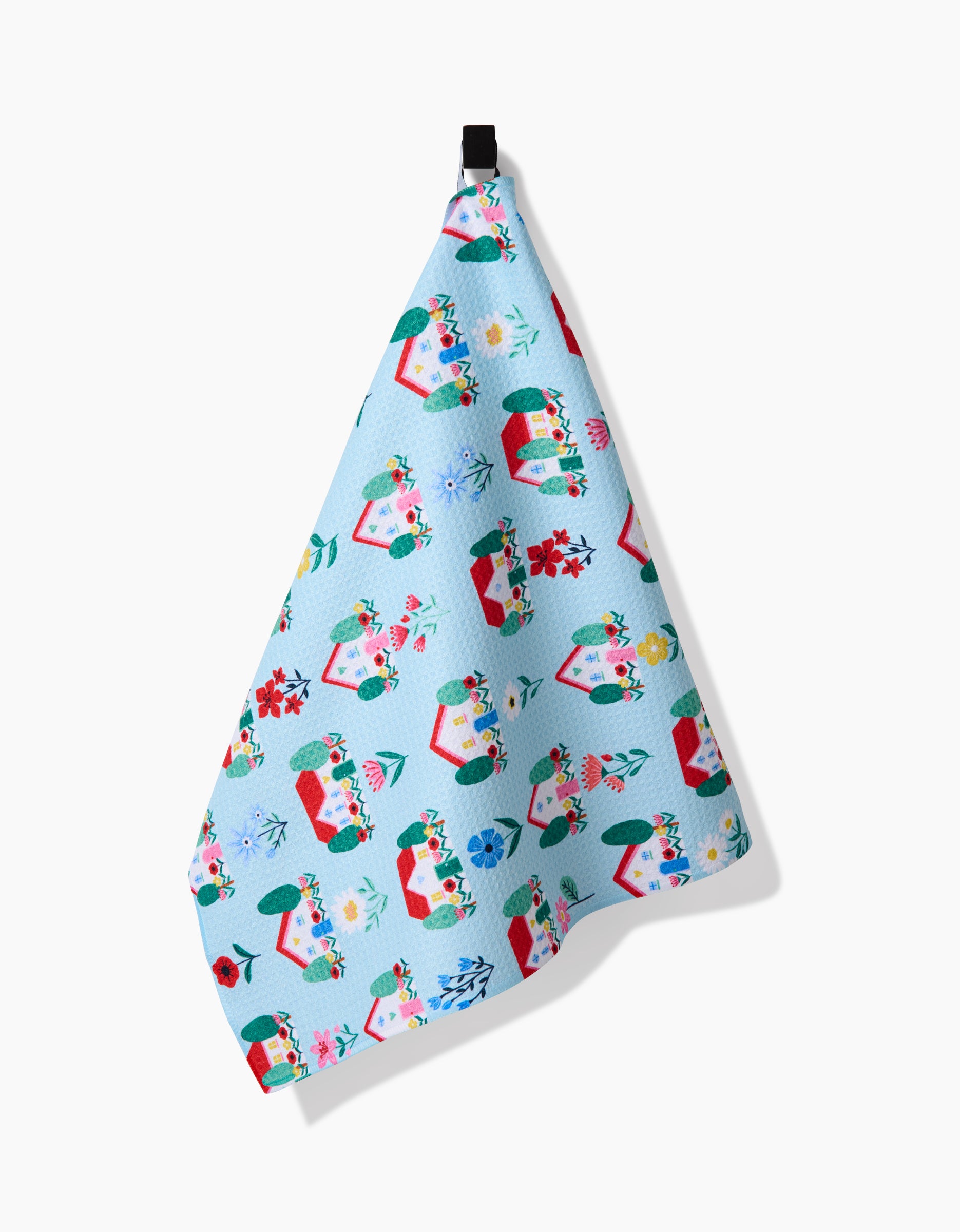 A light blue Geoweave tea towel, Spring Houses by Ceyda Alasar, features colorful floral-filled envelopes and small flowers, hanging from a black loop against a white background.