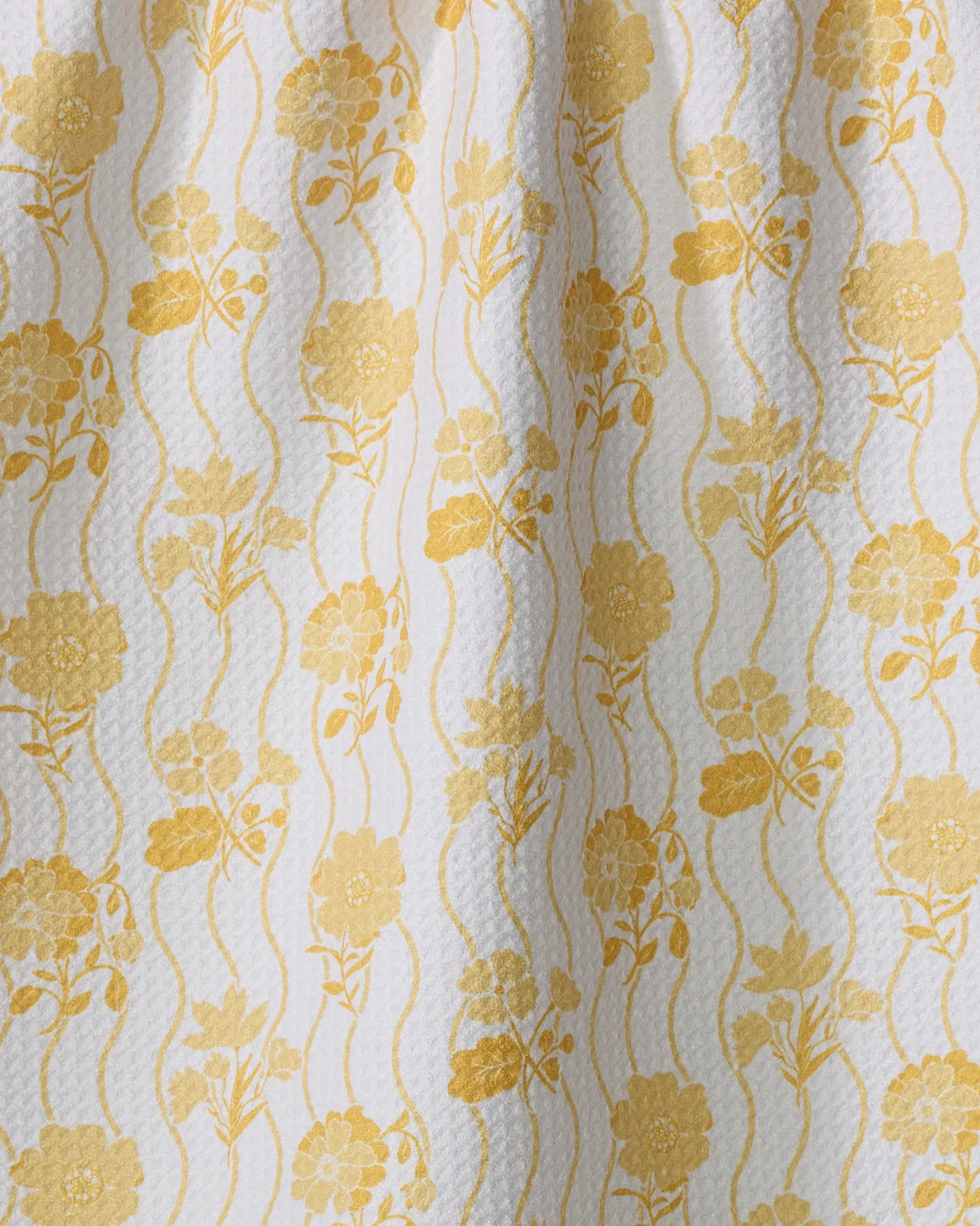 The Danelys Sidron "Spring Wave" tea towel features yellow floral and wavy line patterns on textured white fabric, adding a vintage decorative touch while providing ultra-absorbency for your kitchen.