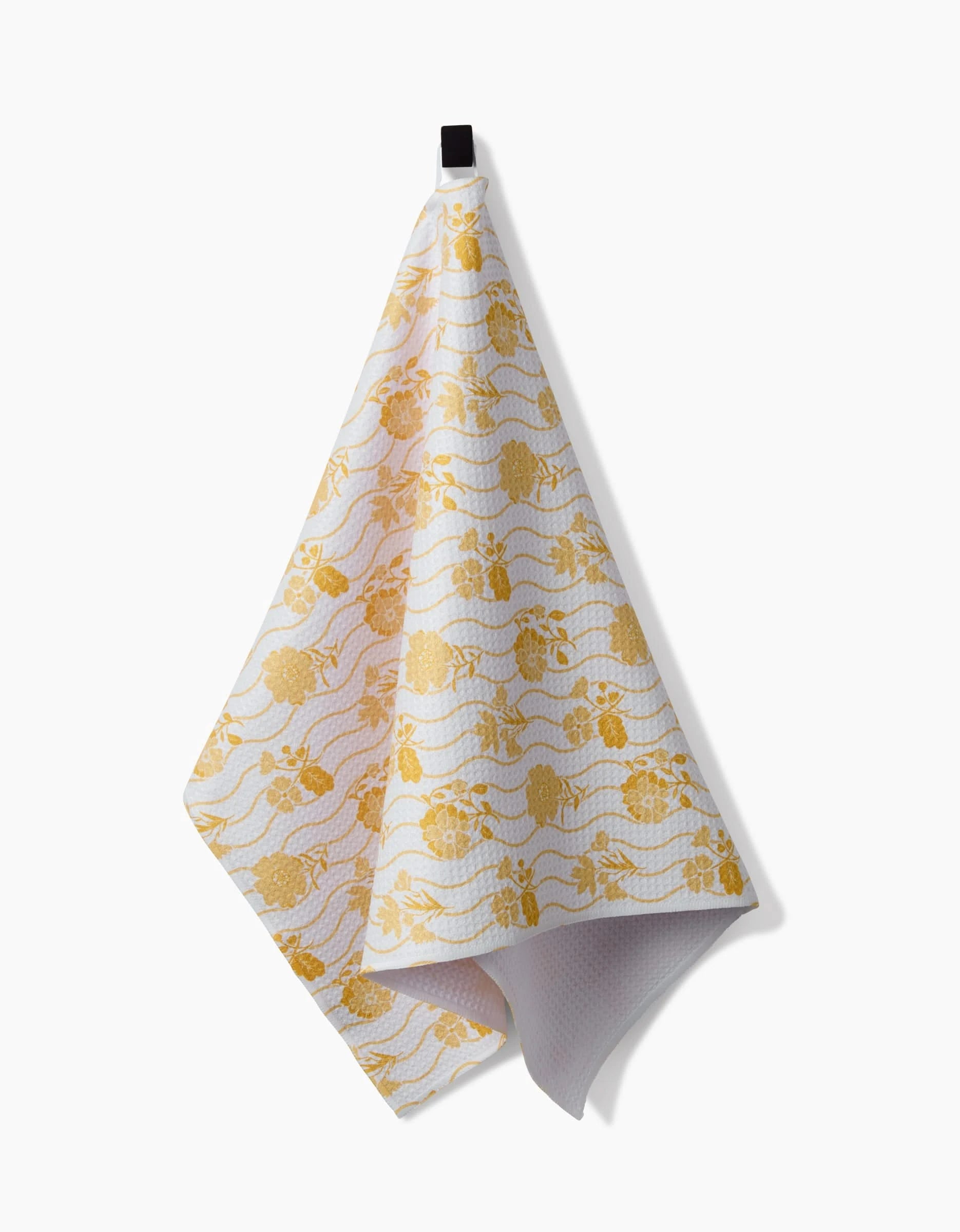 A Danelys Sidron Spring Wave tea towel, crafted from Geoweave fabric with a textured surface and yellow floral pattern, hangs from a black hook against a plain white background.